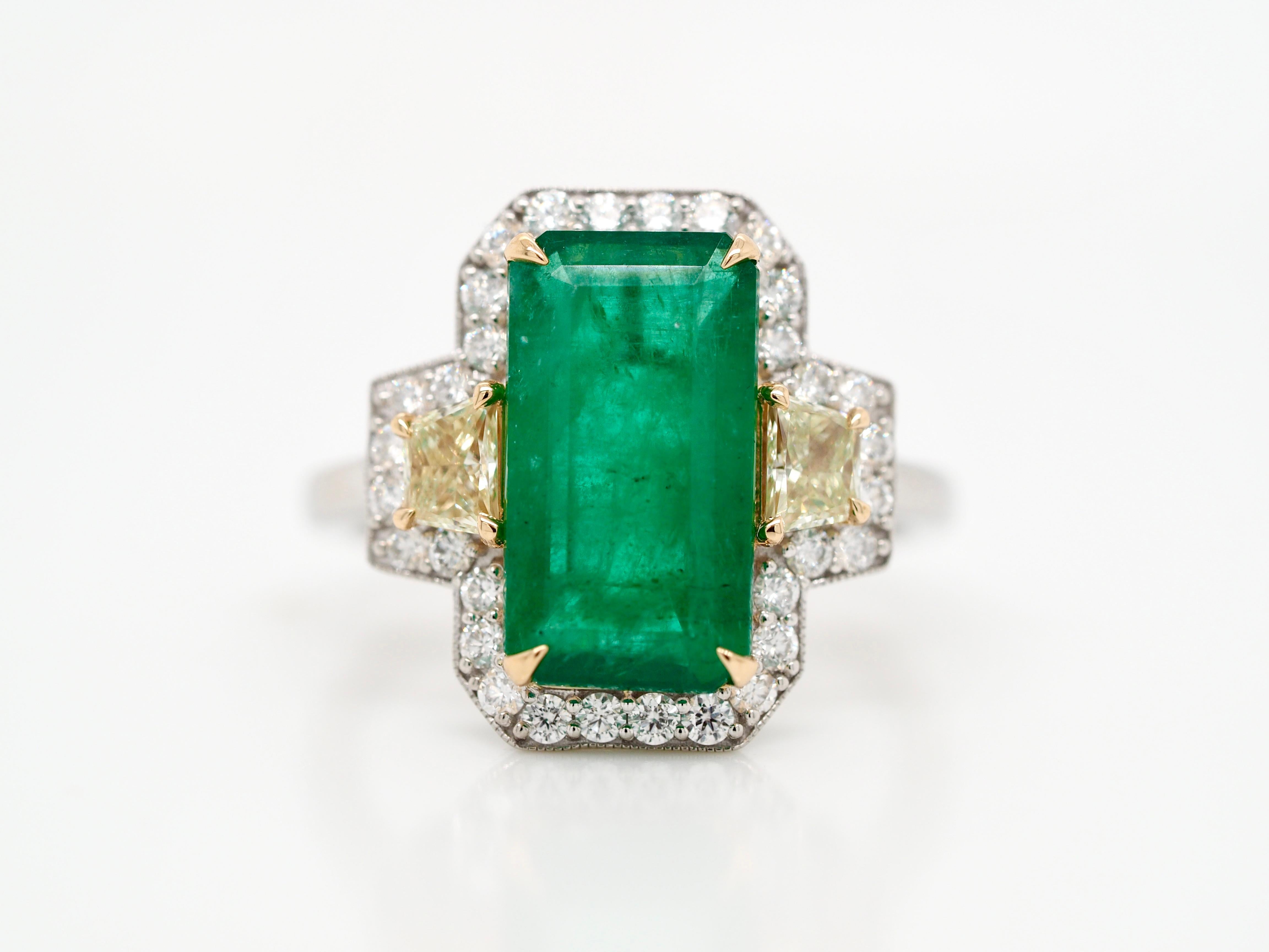 This enchanting ring is memorizing to look at. It has the most beautiful natural emerald, mined from Zambia, set with gold prongs, surrounded by diamond's. On both sides of the emerald, a ray of yellow diamond's brighten up the ring. This is unique