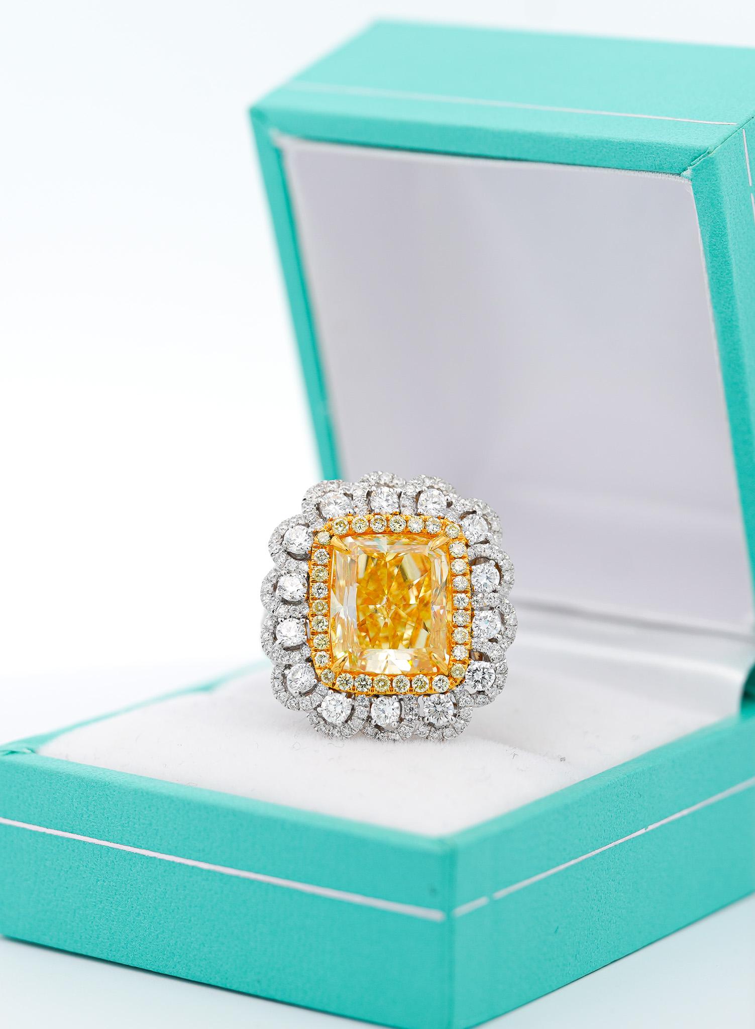 7 carat fancy intense yellow radiant cut diamond set with over 2 carats in white and yellow diamonds. The diamond accents are gracefully made in a curved floral motif design. The ring setting is made in 18 karat white and yellow gold with an open