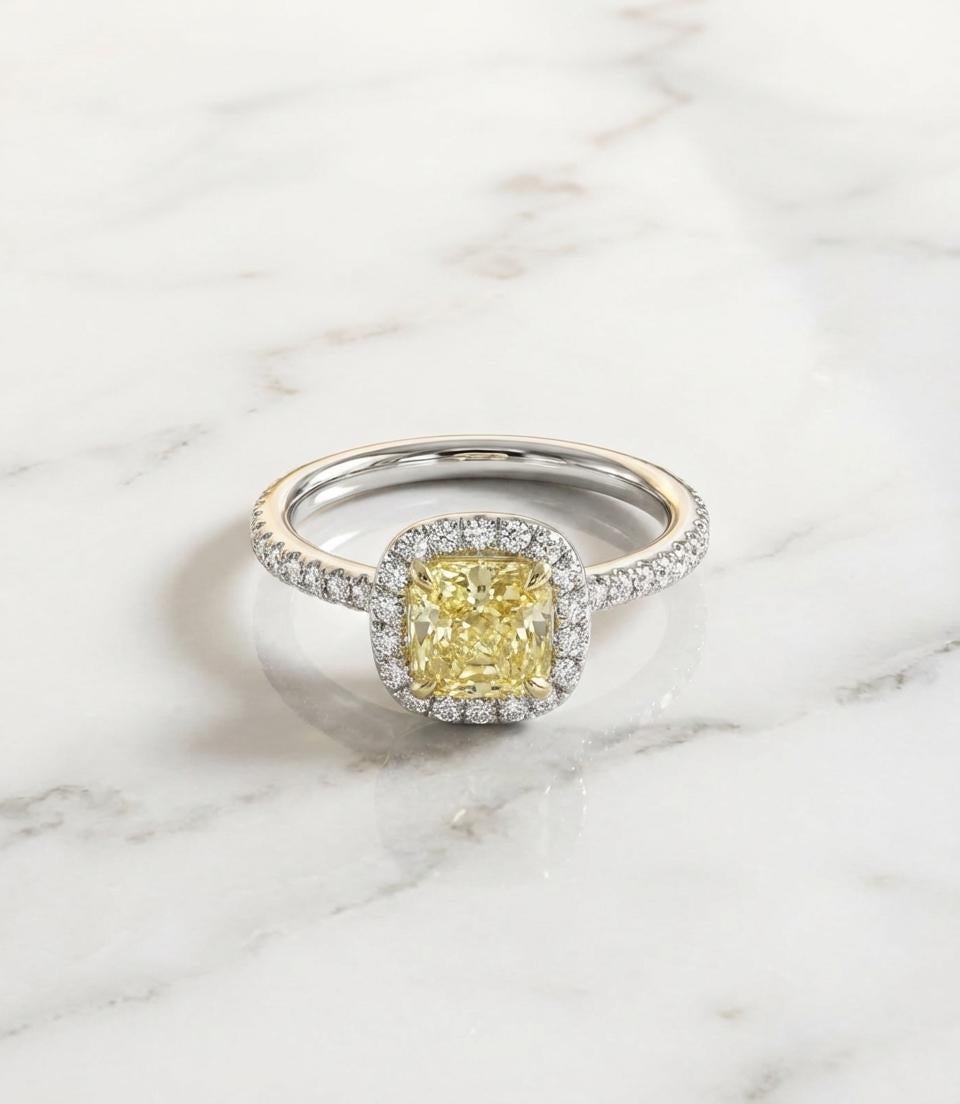 Dieser exquisite Verlobungsring präsentiert einen atemberaubenden GIA-zertifizierten Fancy Intense Yellow-Diamanten, der elegant in der Mitte eines zeitlosen Halo-Designs gefasst ist. Der Hauptdiamant wiegt 1,27 Karat, hat einen wunderschön
