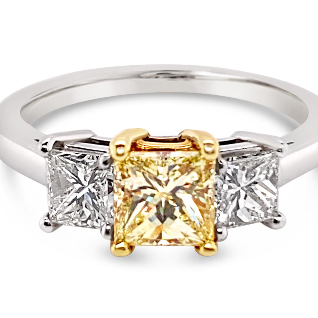 Diamant central de taille princesse de 0,76 carat certifié par le GIA (Fancy Light Yellow), serti latéralement de diamants de taille princesse de 0,81 carat (poids total).  Serti en platine avec une monture en or jaune 18K.
