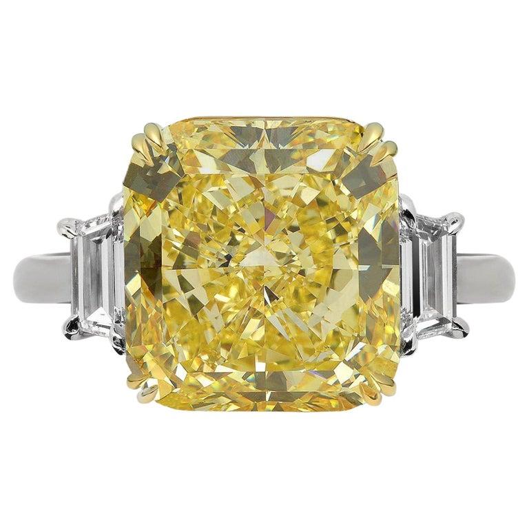 Behold a remarkable GIA Certified Fancy Yellow 10.11 carat cushion cut diamond ring, meticulously crafted in a blend of 18K white and yellow gold. The centerpiece diamond dazzles with its vivid Fancy Yellow color grade, radiating warmth and