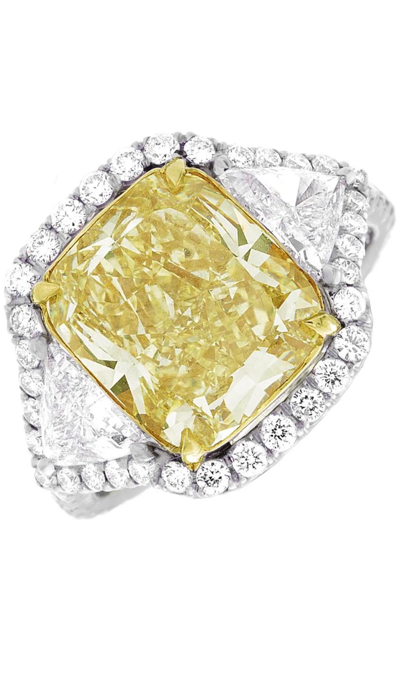 An exquisite and spectacular GIA certified natural fancy yellow diamond, cushion cut, of 5,01 carats 
VVS2 clarity, very clean, and two side natural diamonds trillions cut and round brilliant cut diamonds around the ring, with a total carats of 1,50