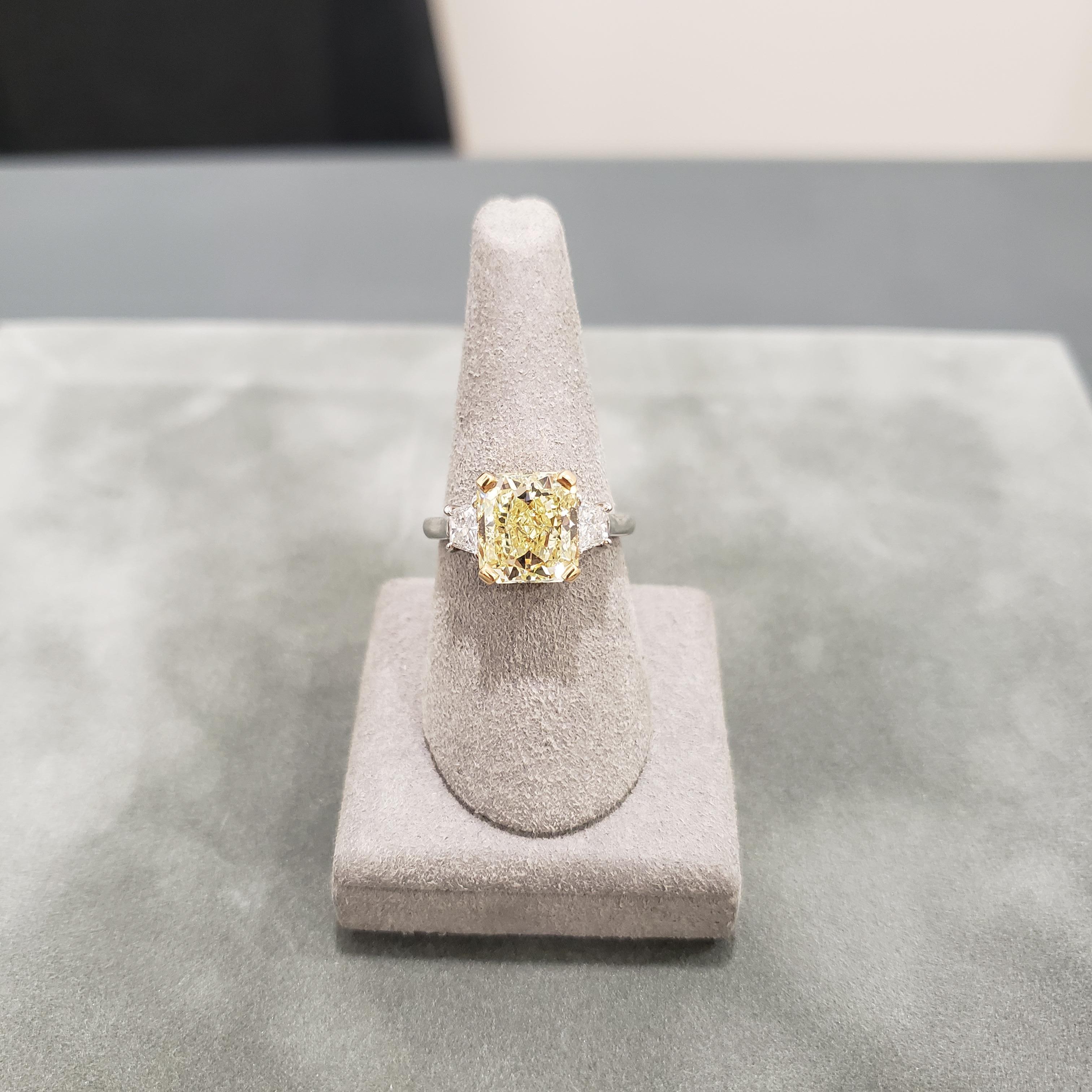 A classic and timeless engagement ring featuring a 4.01 carat radiant cut diamond certified by GIA as Fancy Yellow, VS1 clarity, accented by trapezoid diamonds on each side. Accent diamonds weigh 0.56 carats total. Set in a polished platinum