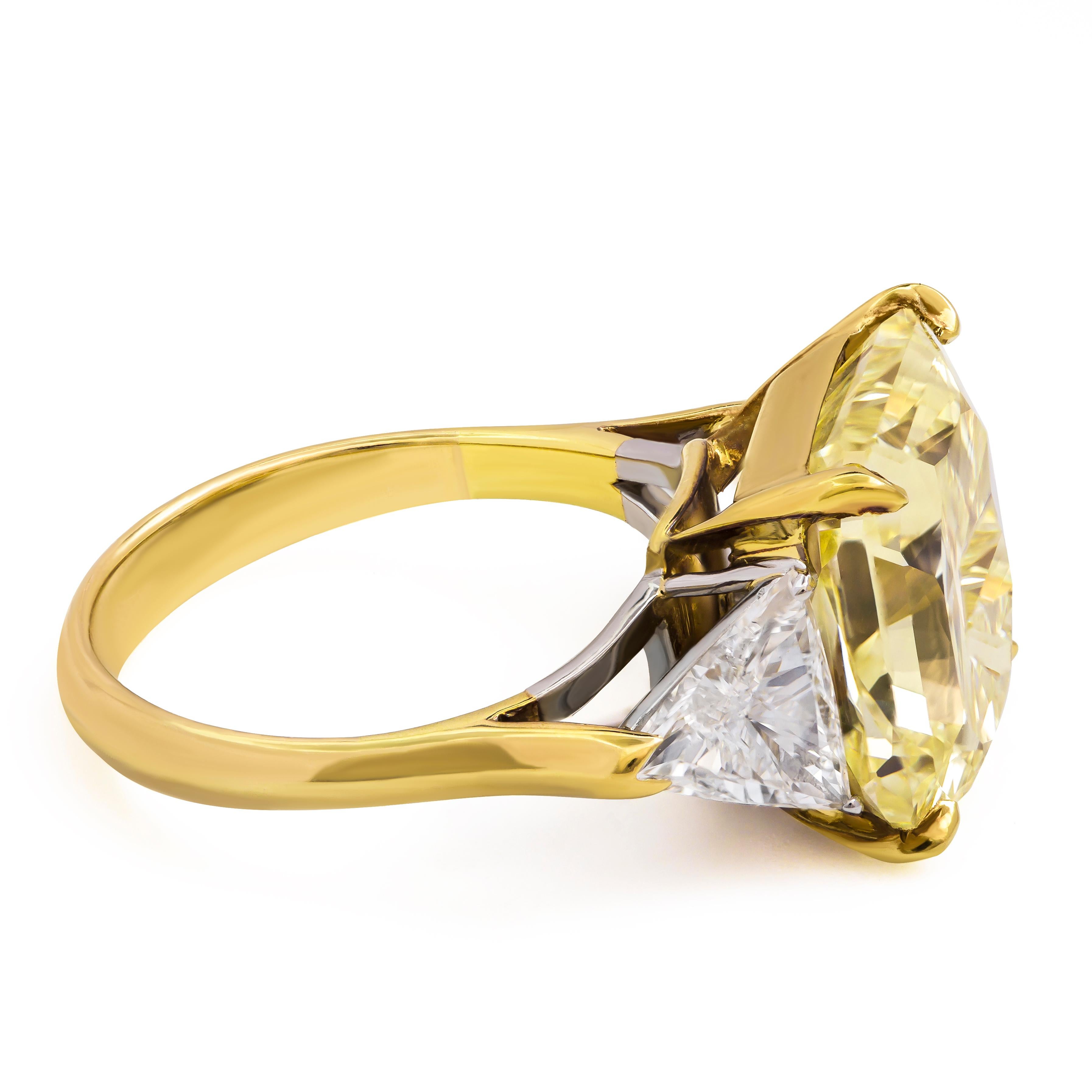 This amazing three-stone engagement ring features a 9.00 carat radiant cut diamond that GIA certified as Fancy Yellow, VS1 clarity. Flanking the center diamond are two brilliant trillion (triangular) diamonds weighing 1.27 carats total. Set in an 18