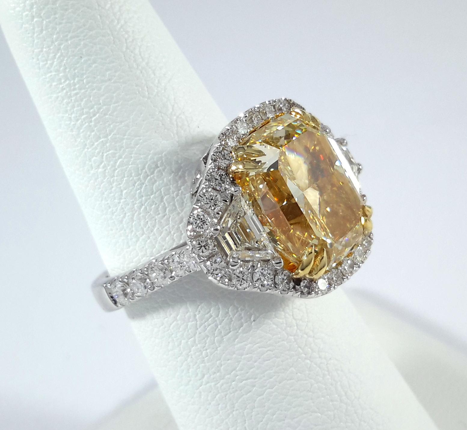 Questo straordinario anello sfoggia un impressionante diamante naturale Fancy Yellow da 8,11 carati, certificato da GIA con un grado di chiarezza VS2 e un'eccellente lucentezza e simmetria. La pietra centrale ha un taglio radiante con angoli