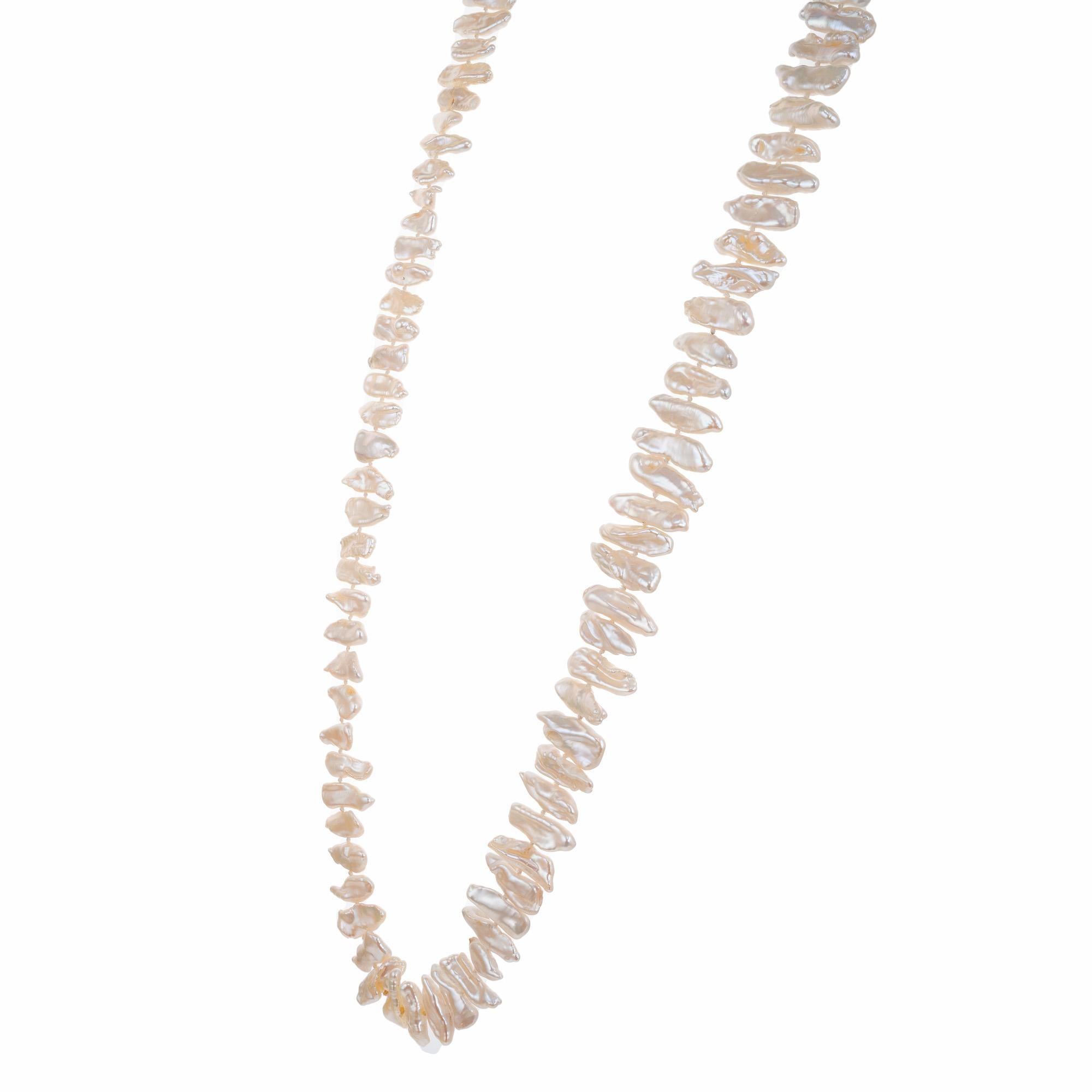 Indulge in the unique elegance of our GIA Certified Freshwater Baroque Pearl Necklace. This necklace is strung with 96 creme white, freshwater pearls showcasing their distinctive shape and iridescence. 28 inches in length. The GIA certified as