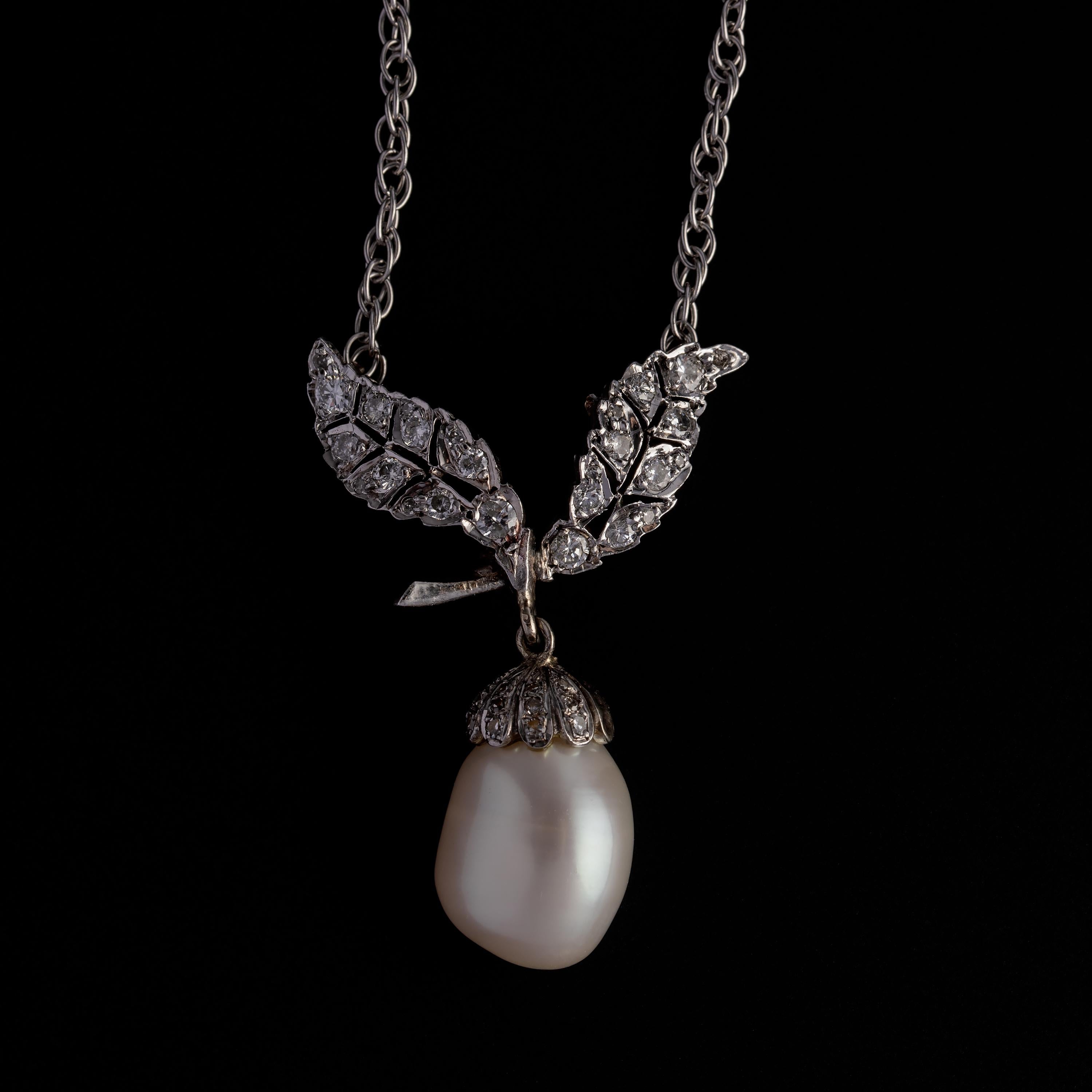 A huge (12.16mm x 9.26mm) GIA certified cultured freshwater semi-baroque pearl dangles freely from a pair of silvery, diamond-set leaves in this Victorian-revival pendant. This chic circa-1960s necklace measures 23