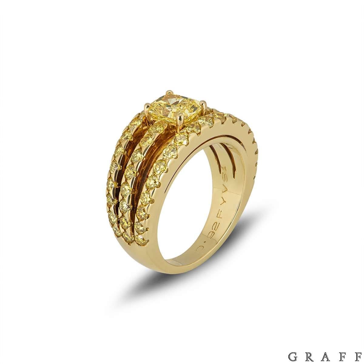 A Graff diamond ring in 18k yellow gold. The ring is set to the centre with 0.92ct rectangular modified brilliant fancy vivid yellow diamond, laser inscribed 'GRAFF'. The central diamond is claw set, positioned in the middle of three bands set with