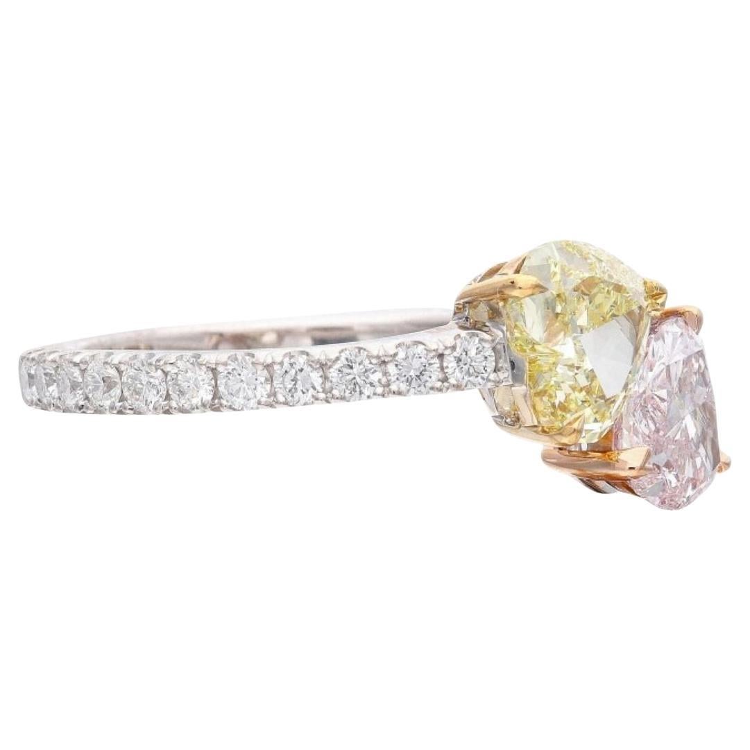An exquisite Gold Fancy Light Pink and Fancy Yellow Diamond Bypass Ring, an enchanting masterpiece designed to captivate hearts. This resplendent ring features a Fancy Yellow heart-shaped diamond, boasting a weight of 0.84 carats, and a dazzling