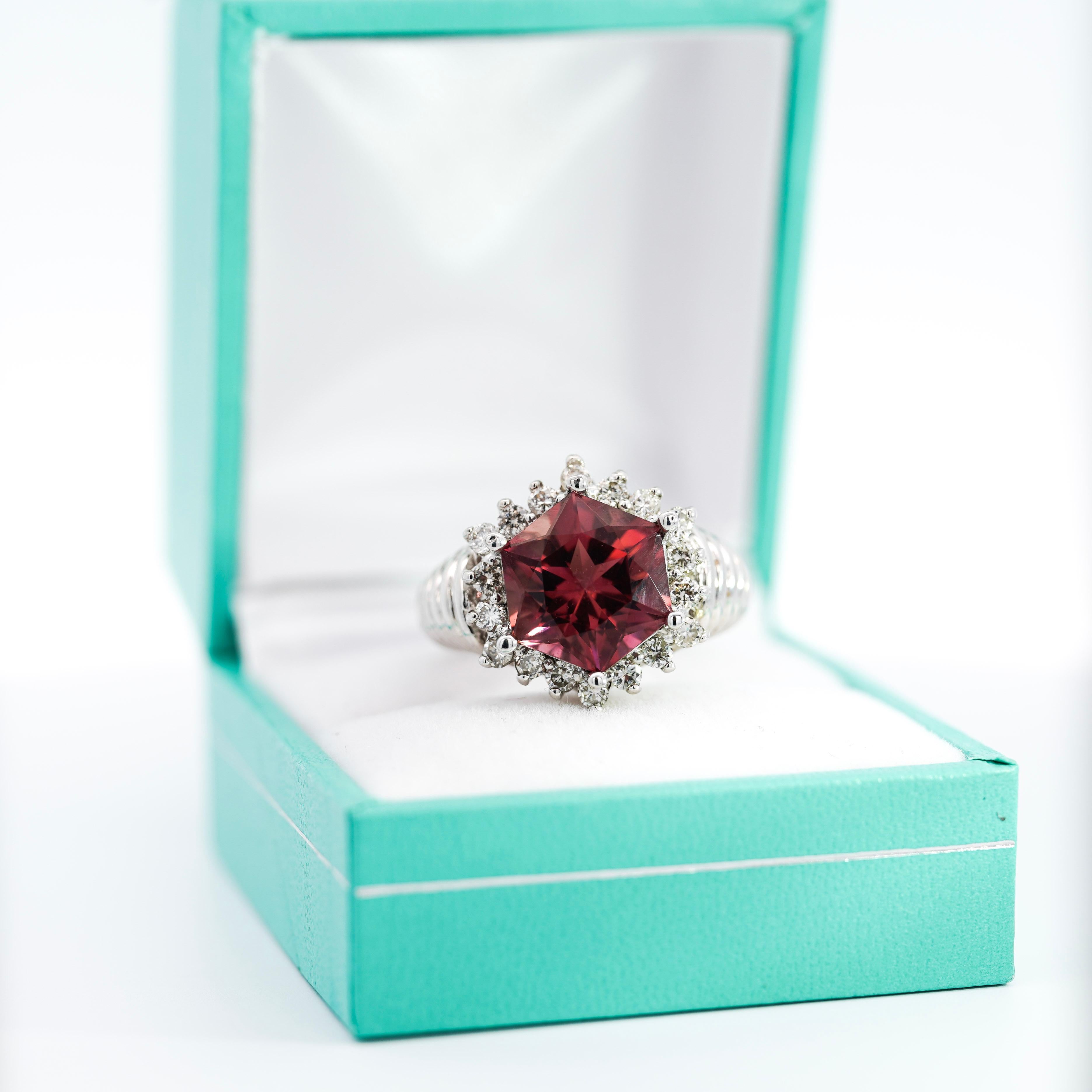 This ring features a GIA Certified Natural Pink tourmaline, with a hexagonal cut. Paired with round cut near-colorless diamonds, placed within the halo of the ring. Made from 18k white gold, this ring has a textured ribbed shank adding to the