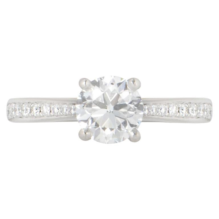 A platinum diamond engagement ring by Laing. The round brilliant cut diamond is in a four claw setting with a weight of 1.02ct, is G colour and SI1 in clarity. The ring has diamond set shoulders totalling 0.10ct, well matched in colour and clarity