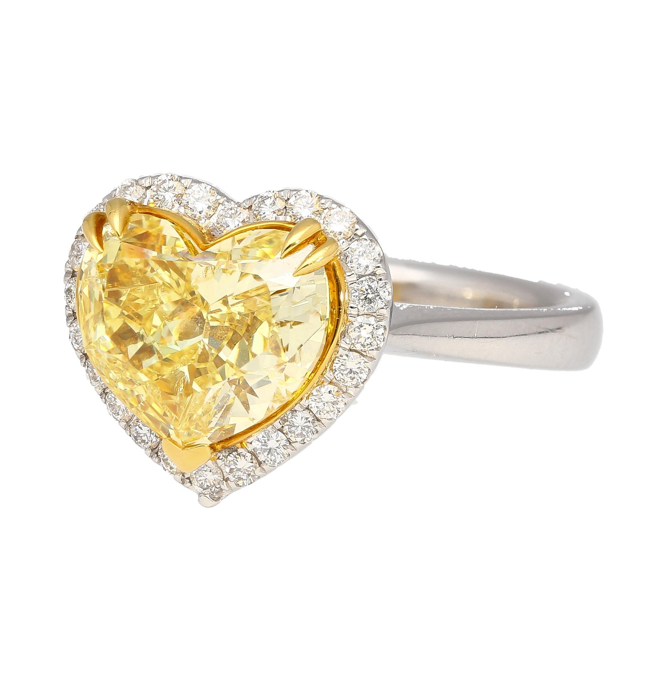 GIA certified 3.32 carat Fancy Intense Yellow natural diamond engagement ring with a round cut white diamond halo. Set in 18 karat solid white and yellow gold. The center stone is a true investment piece. Heart cut, GIA certified, and radiating with