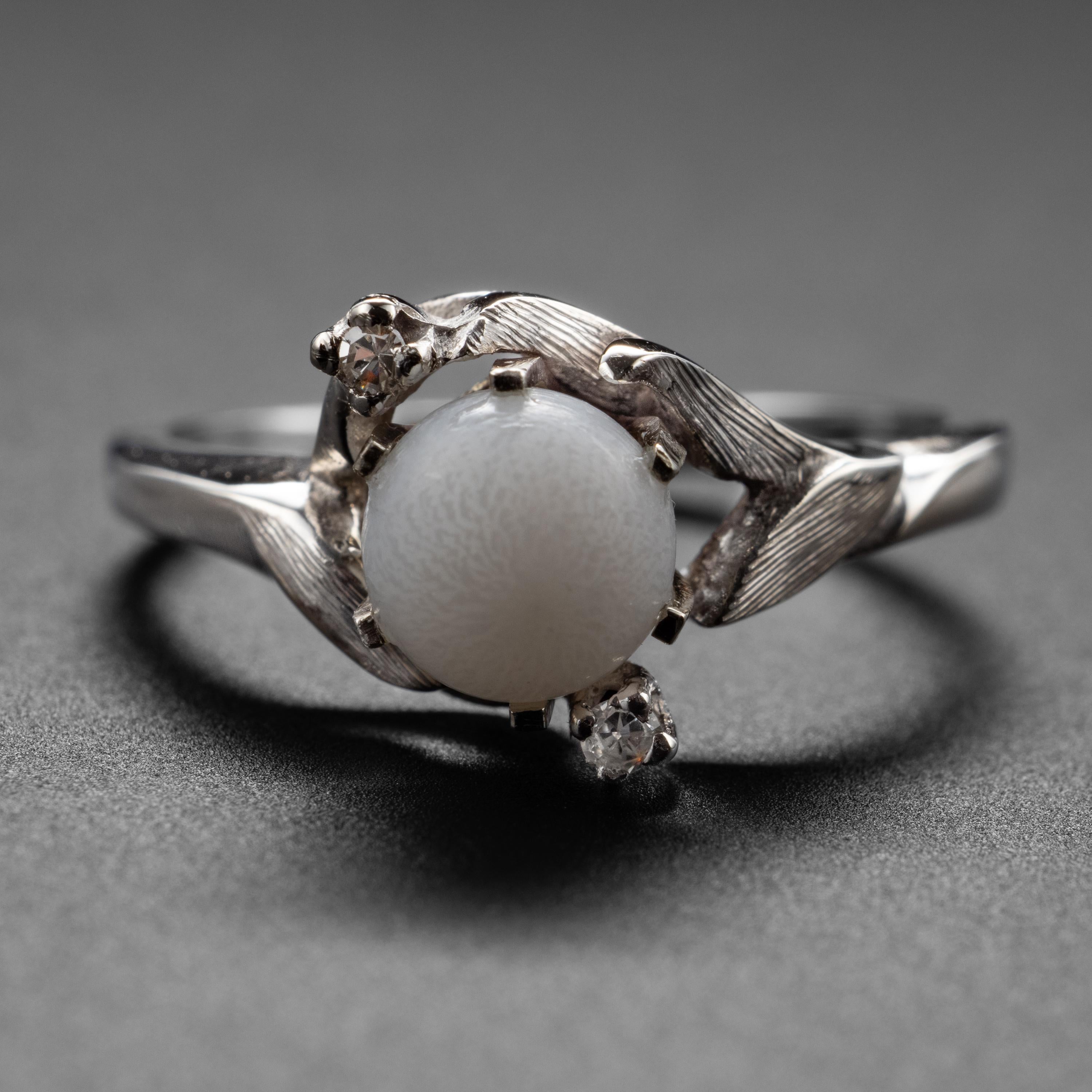 In einem 14-Karat-Weißgoldring mit Diamanten aus den frühen 1950er Jahren ist eine faszinierende und seltene Perle eingearbeitet, von der Sie wahrscheinlich gar nicht wussten, dass es sie gibt: eine natürliche Salzwasser-Muschelperle. Die meisten
