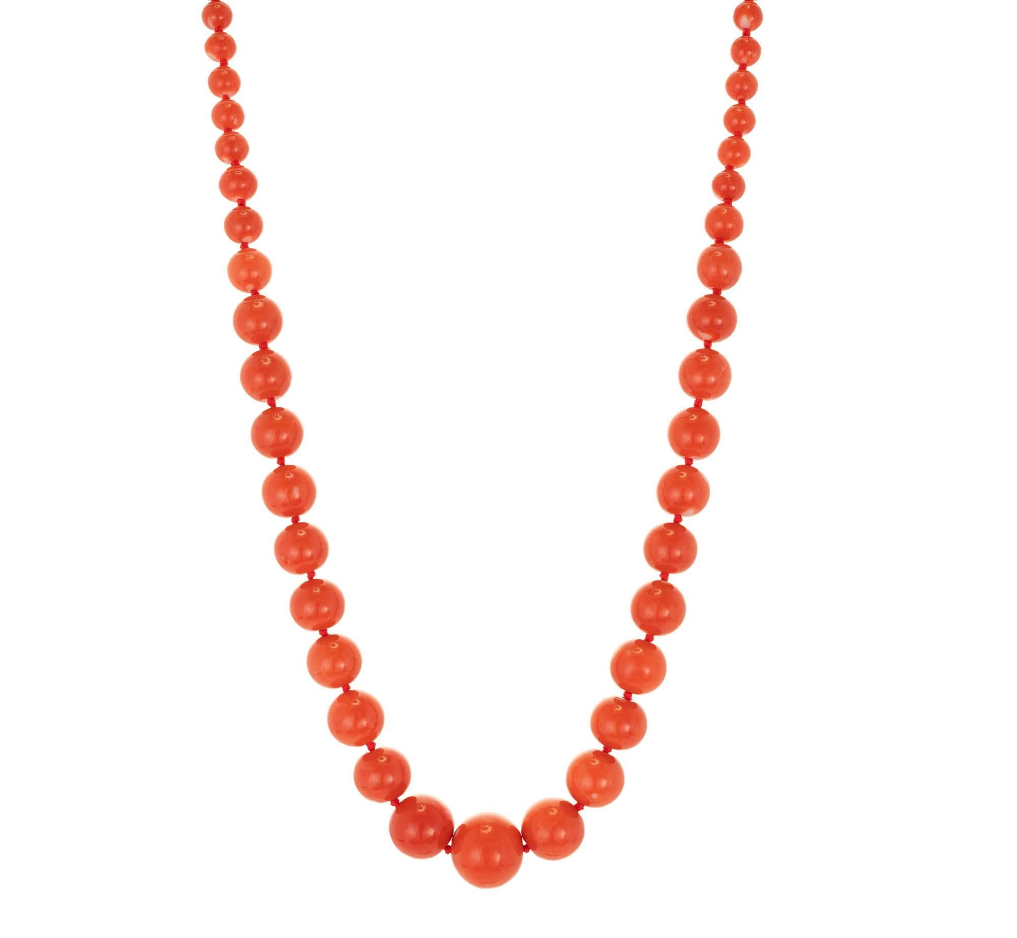 Single strand graduated natural coral necklace with a yellow gold diamond clasp. Composed of 57 reddish orange natural coral beads measuring from 15mm in diameter at front to 6mm in diameter at back. Secured by a buccelatti domed and oval shape