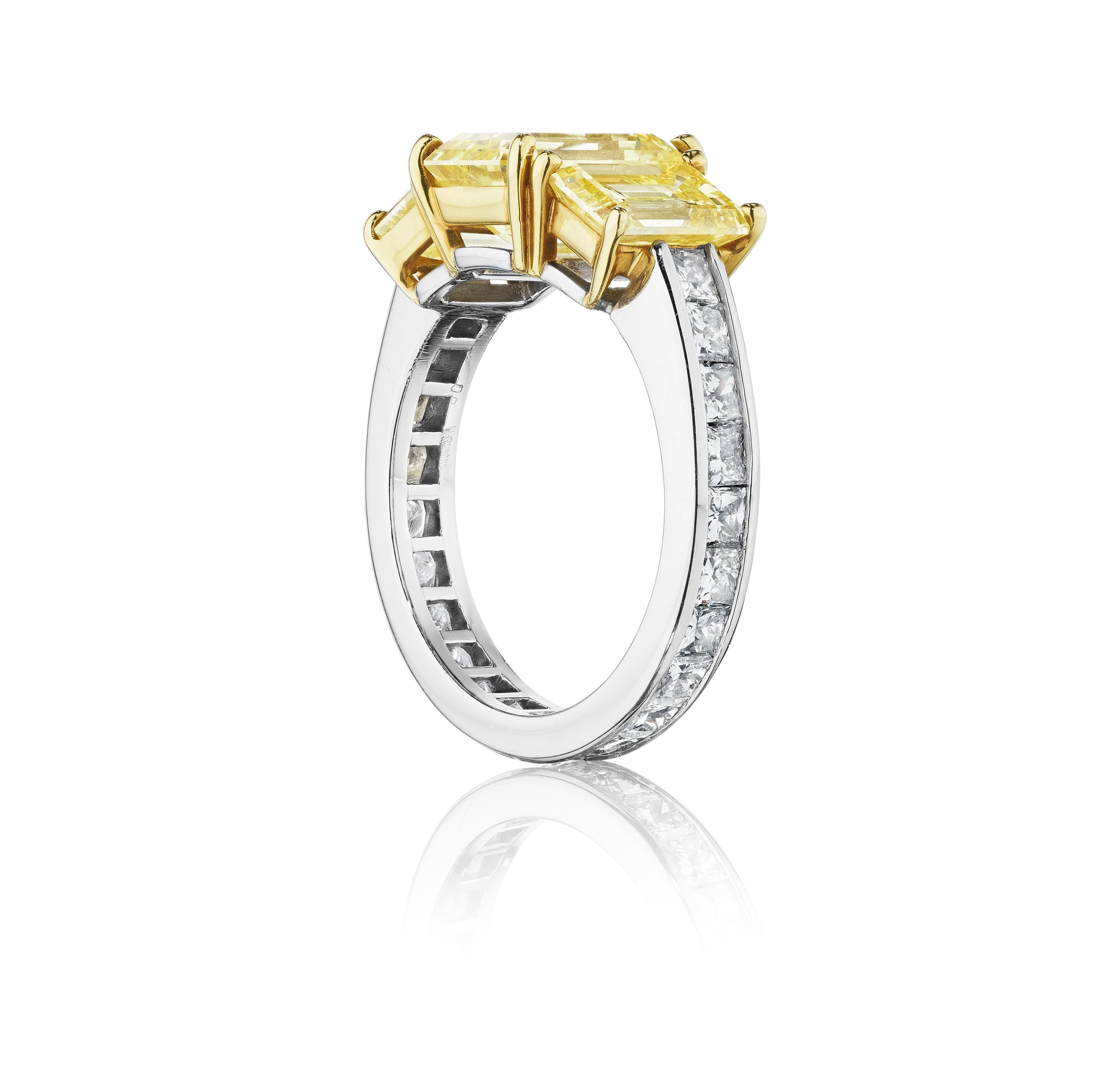 A ring centered by three slightly graduating prong-set, emerald-cut fancy intense yellow diamonds, offset by a channel set band of princess-cut diamonds; mounted in 18K yellow gold and platinum
• 3 emerald-cut yellow diamonds, weighing 1.06, 1.02,