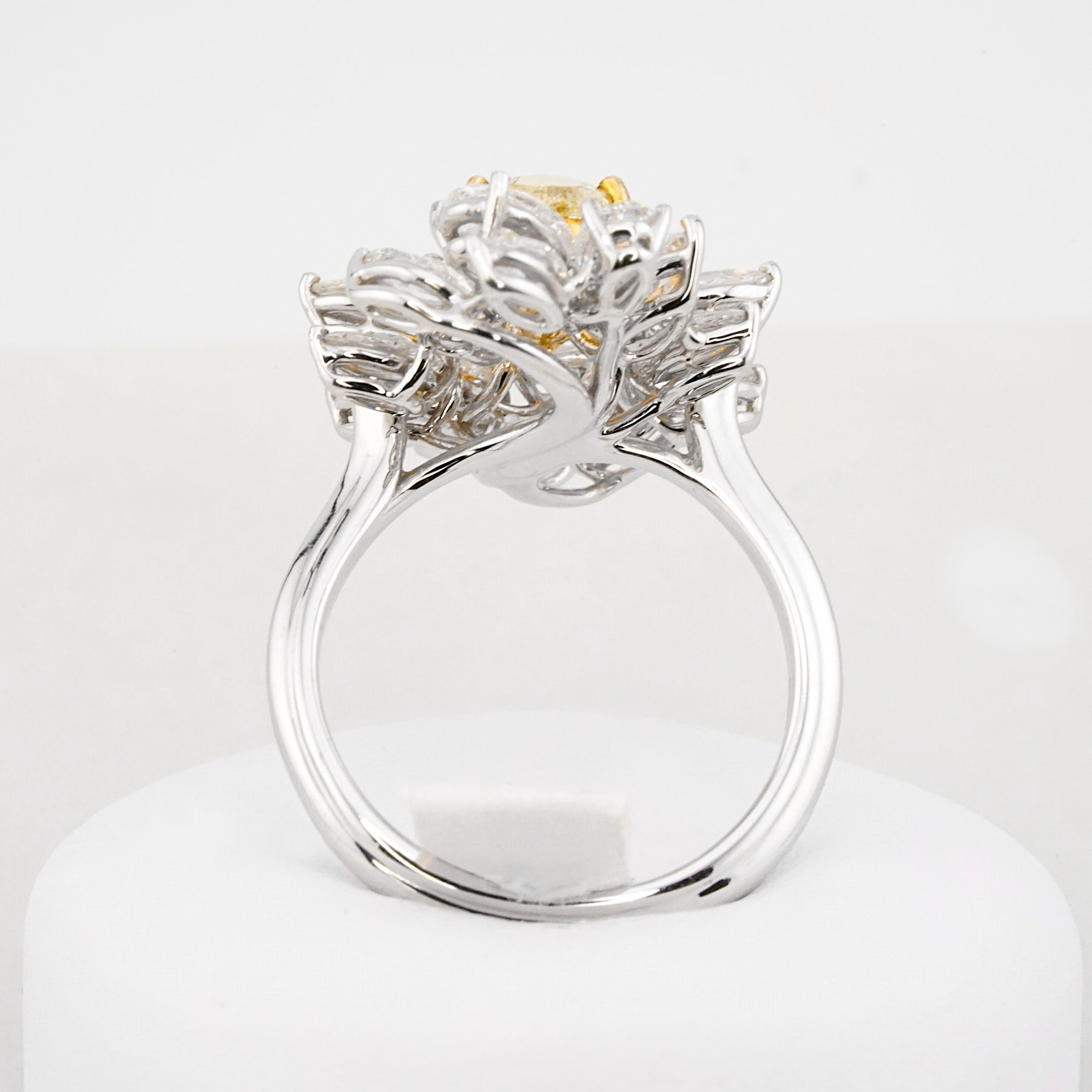 Indulge in the sheer opulence of our latest creation — an extraordinary cocktail ring that effortlessly captivates the beholder. At its heart, a GIA certified pear-cut fancy light yellow diamond, weighing a resplendent 1.35 carats, takes center