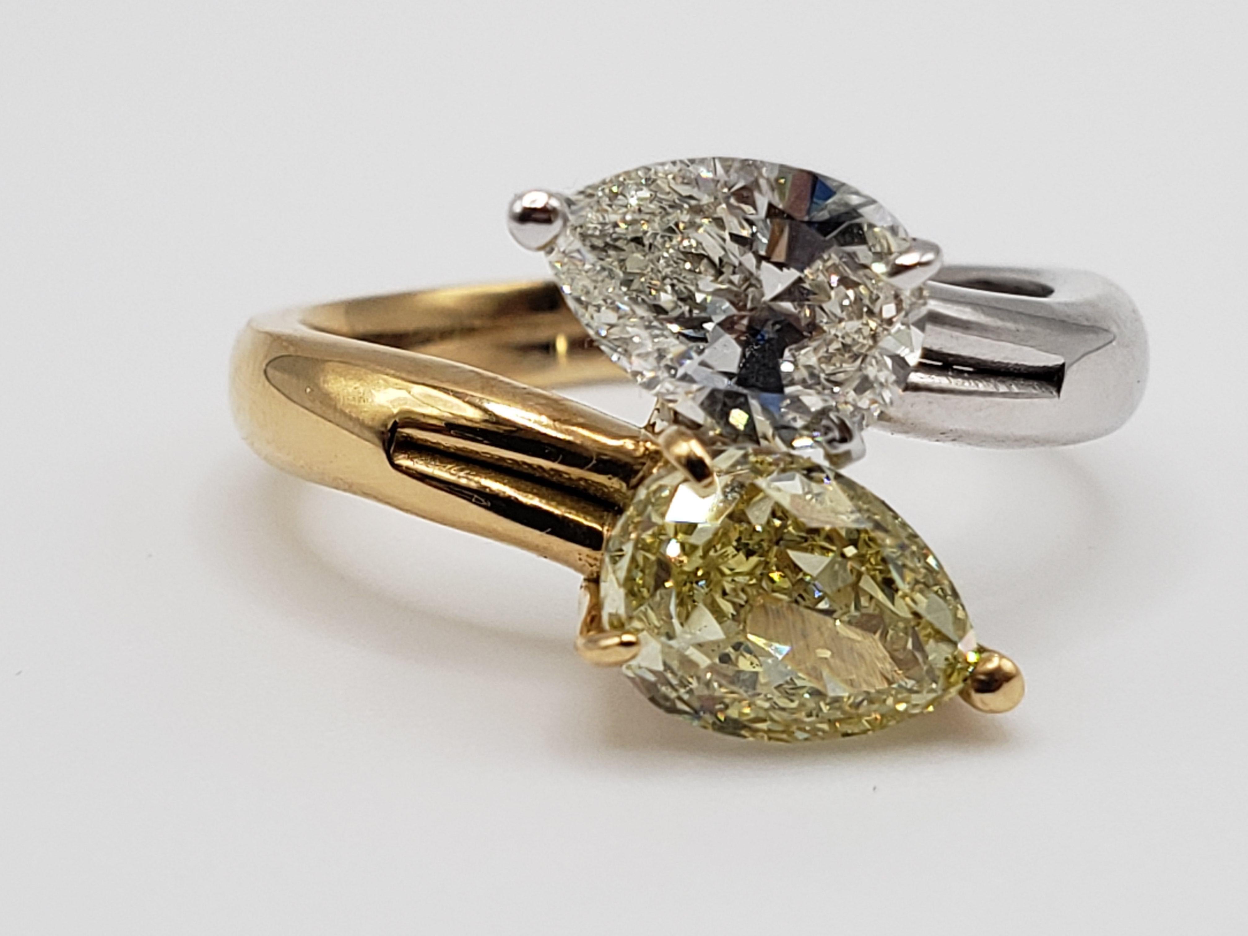 An extraordinary handmade diamond ring crafted from 14K two-tone (white and yellow) gold. It features two individual teardrop/pear-shaped natural diamonds. The GIA-certified natural fancy yellow diamond weighs 1.52 carats, exhibits even color