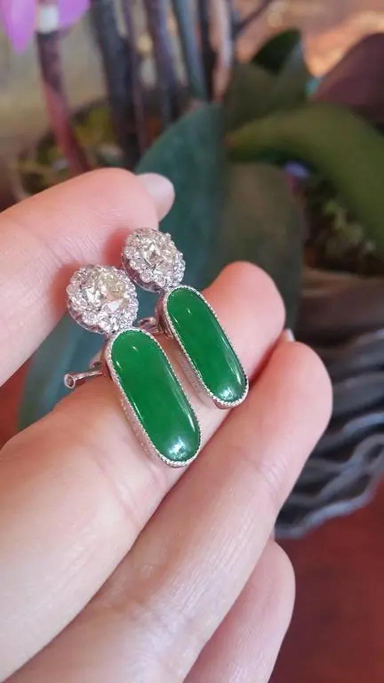 GIA Certified Jadeite Jade Diamond Earrings features two beautifully translucent and open-backed Oval Jadeite Jade stones weighing 6.93 carats, set with two large Round Brilliant Diamonds surrounded by smaller Round Brilliant Diamonds set in