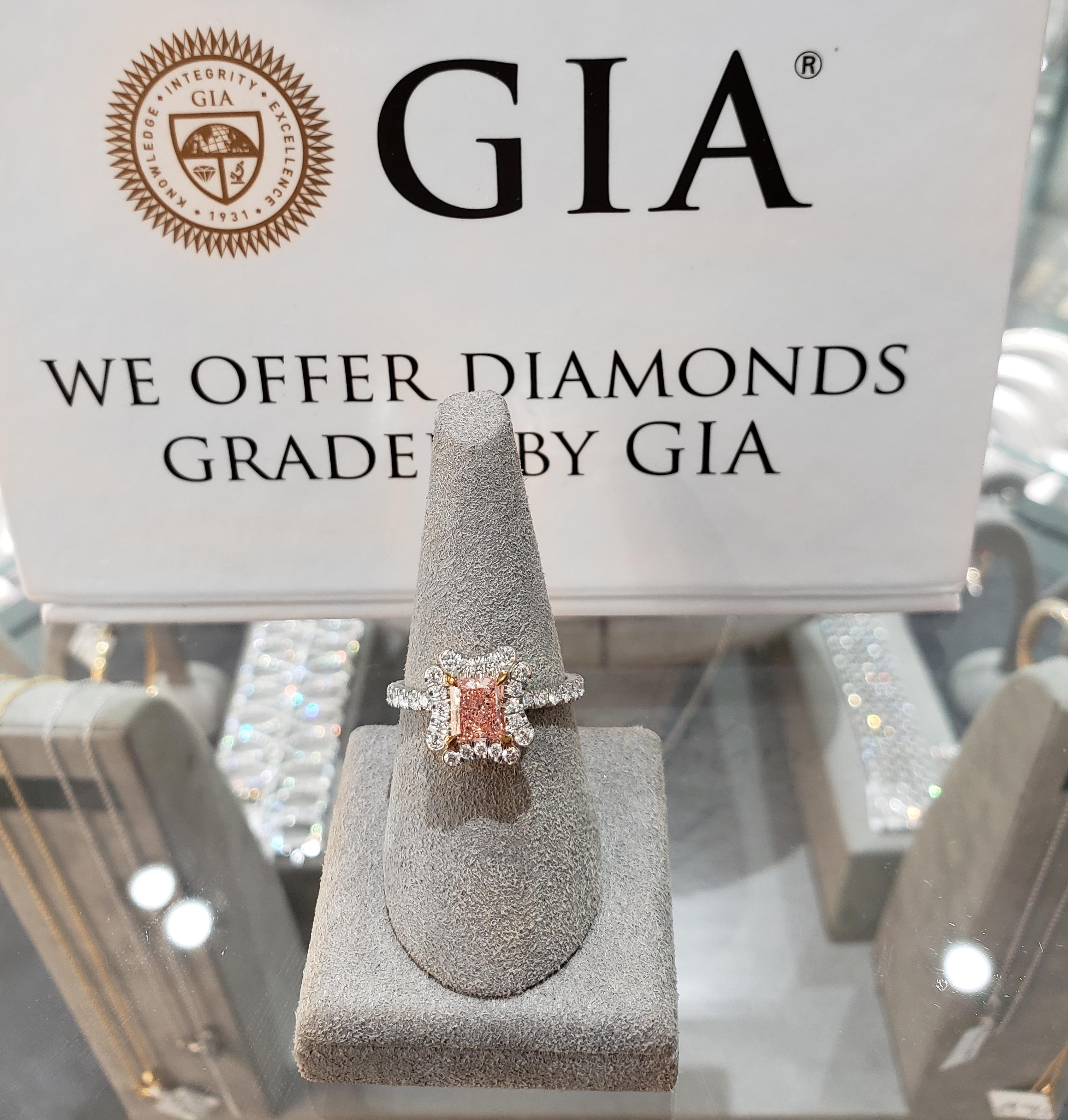 Rare and elegantly made halo engagement ring featuring a vibrant 0.88 carat radiant cut pink diamond that GIA certified as fancy brownish pink, SI1 in clarity, set in an 18k yellow gold four prong setting. The center stone is surrounded by an