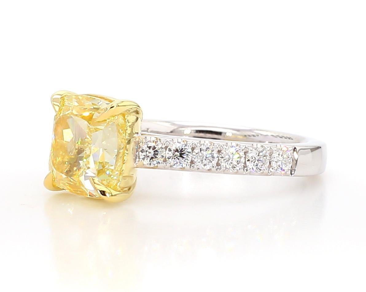 RareGemWorld's beautiful GIA certified diamond ring. Mounted in a beautiful 18K Yellow and White Gold setting with a natural cushion cut yellow diamond. The yellow diamond is surrounded by round natural white diamond melee. This ring is guaranteed