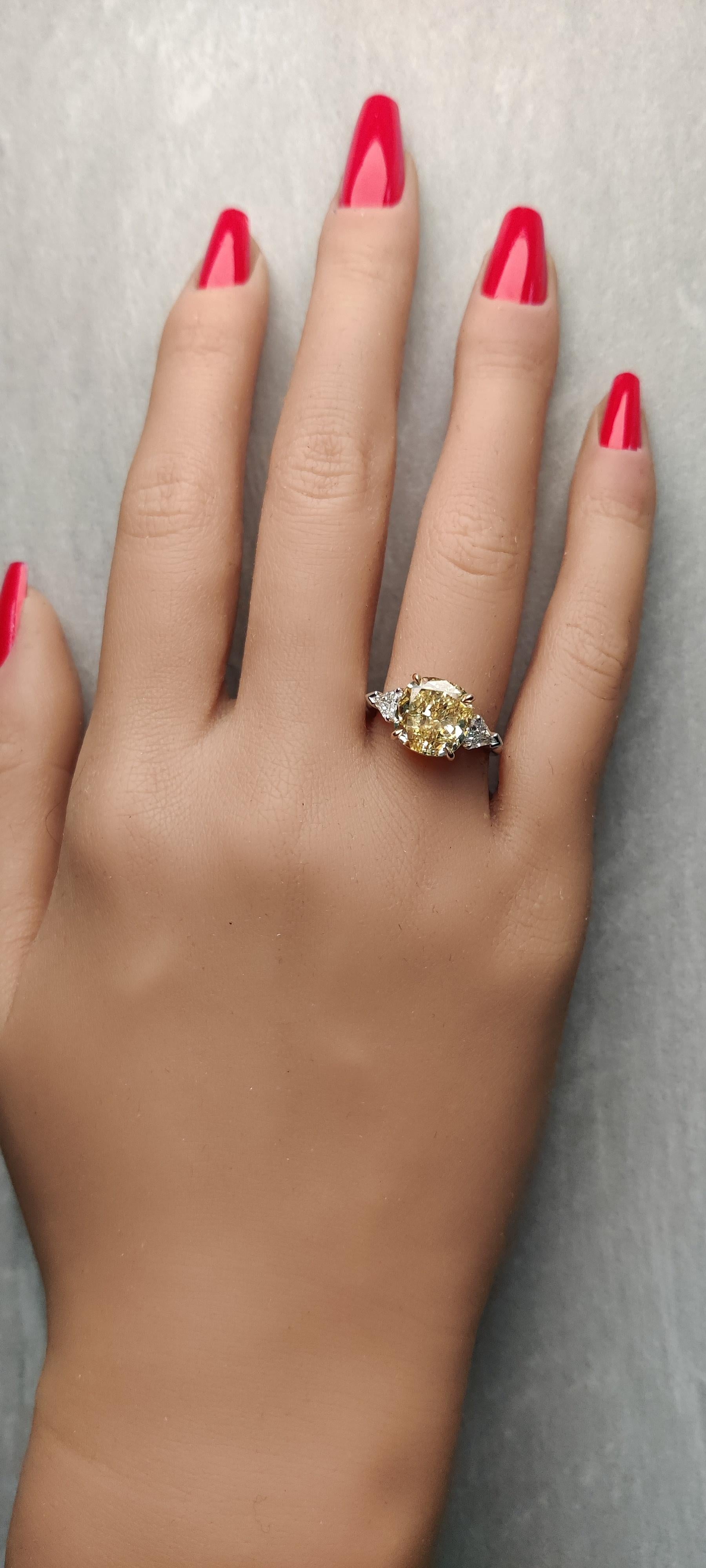 RareGemWorld's classic diamond ring. Mounted in a beautiful 18K Gold and Platinum setting with a natural cushion cut yellow diamond. The yellow diamond is surrounded by natural two kite cut white diamonds. This ring is guaranteed to impress and