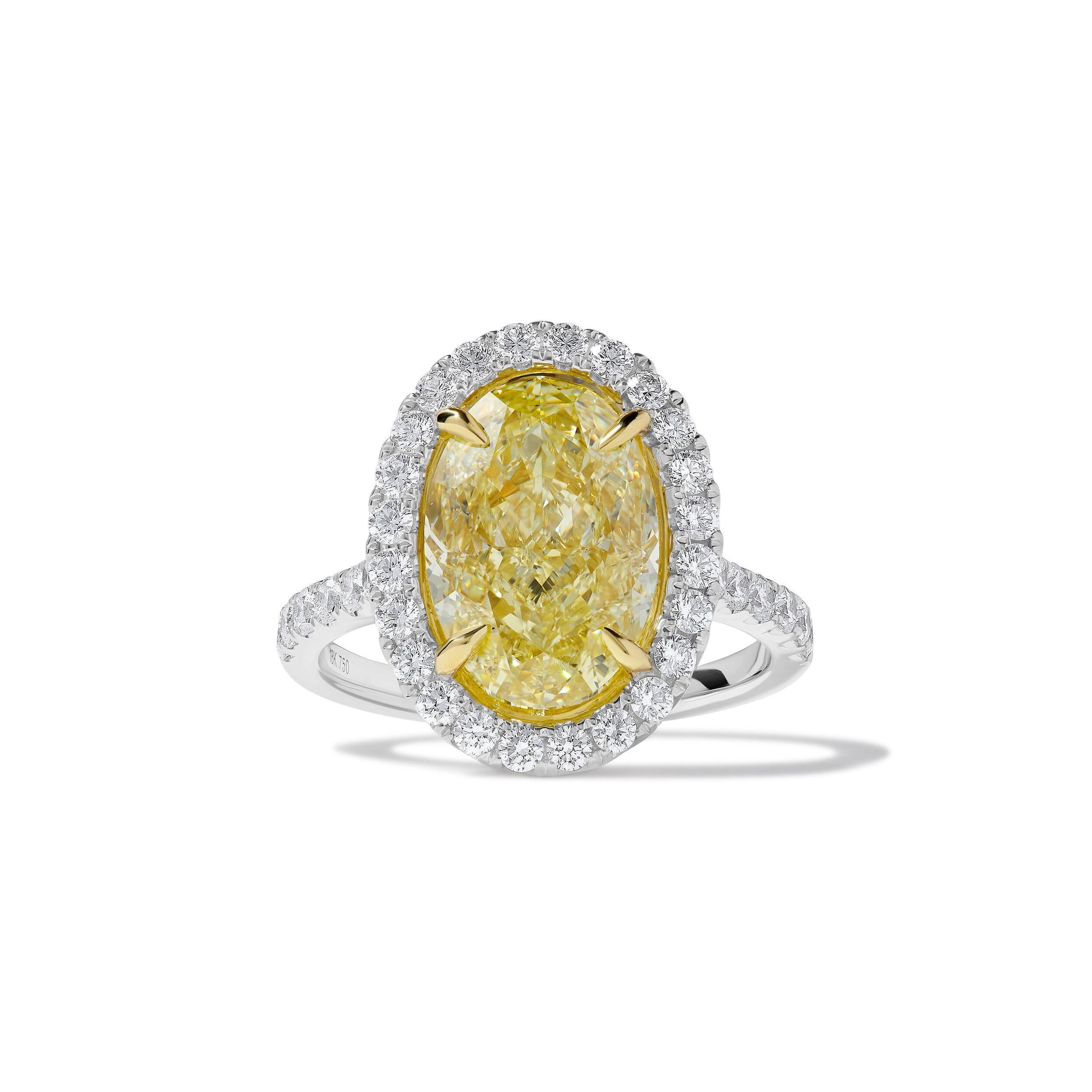 RareGemWorld's classic GIA certified diamond ring. Mounted in a beautiful 18K Yellow and White Gold setting with a natural oval cut yellow diamond. The yellow diamond is surrounded by round natural white diamond melee. This ring is guaranteed to