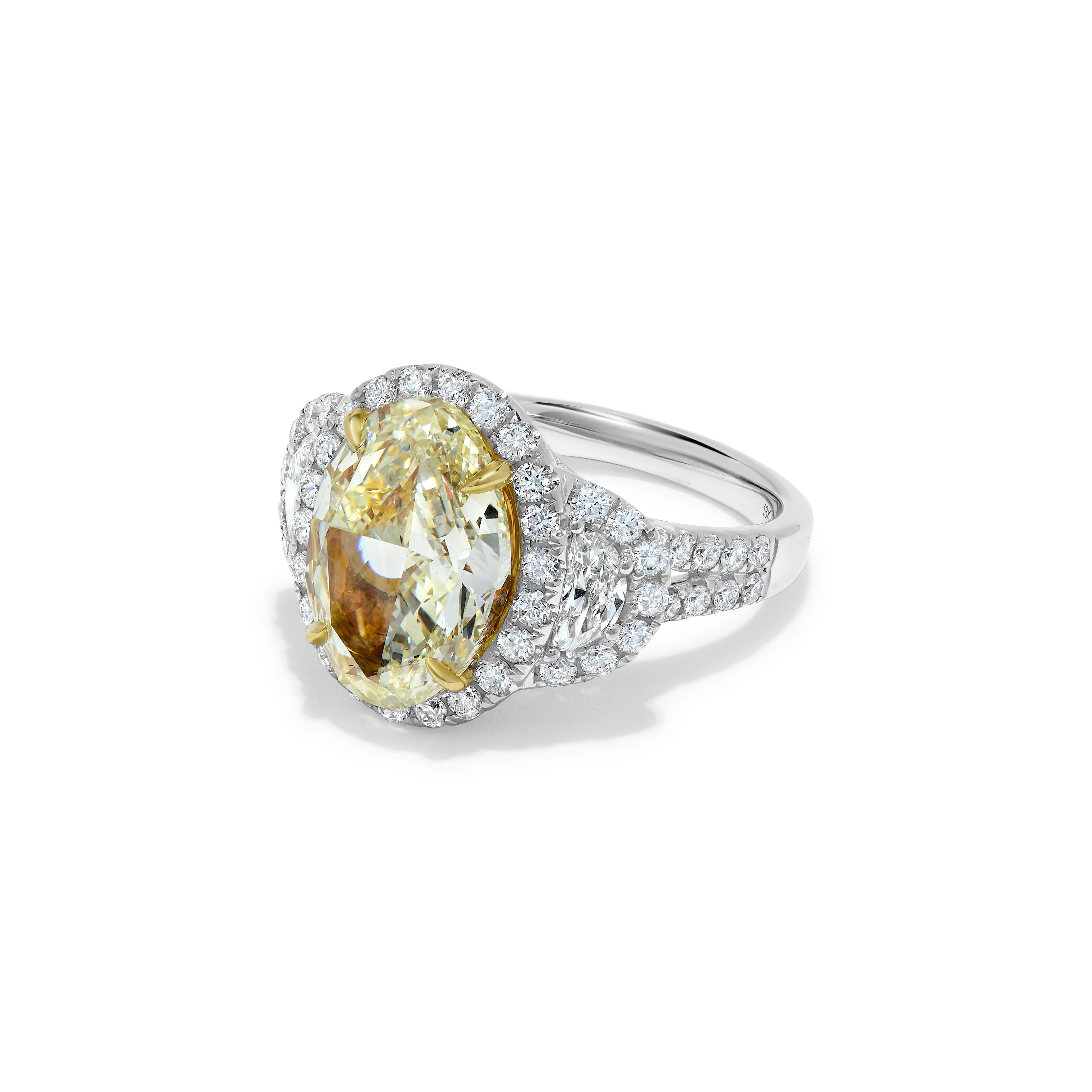 RareGemWorld's classic GIA certified diamond ring. Mounted in a beautiful 18K Yellow and White Gold setting with a natural oval cut yellow diamond. The yellow diamond is surrounded by small round natural white diamond melee and two natural half-moon