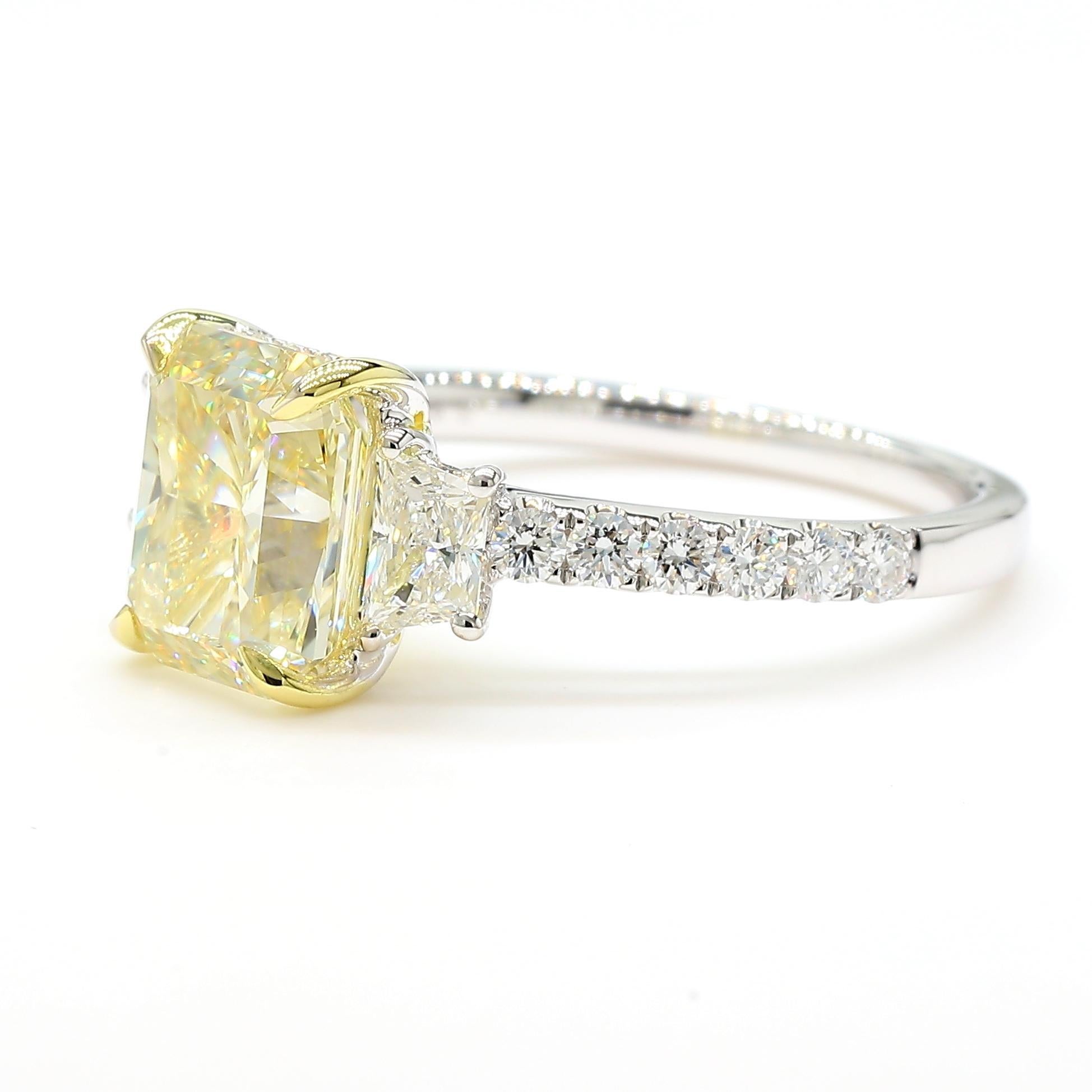RareGemWorld's beautiful diamond ring. Mounted in a beautiful 18K Yellow and White Gold setting with a natural radiant cut yellow diamond. The yellow diamond is surrounded by two natural trapezoid cut white diamonds and round natural white diamond