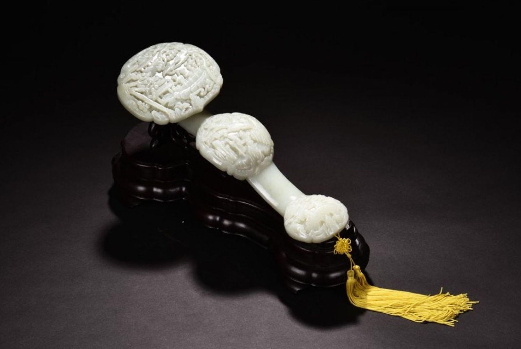 Cette sculpture de Ruyi est finement travaillée en jade néphrite naturel vert clair et blanc, représentant de manière complexe trois scènes narratives du couple de la longévité, un motif traditionnel symbolisant la longévité et le bonheur. Le couple
