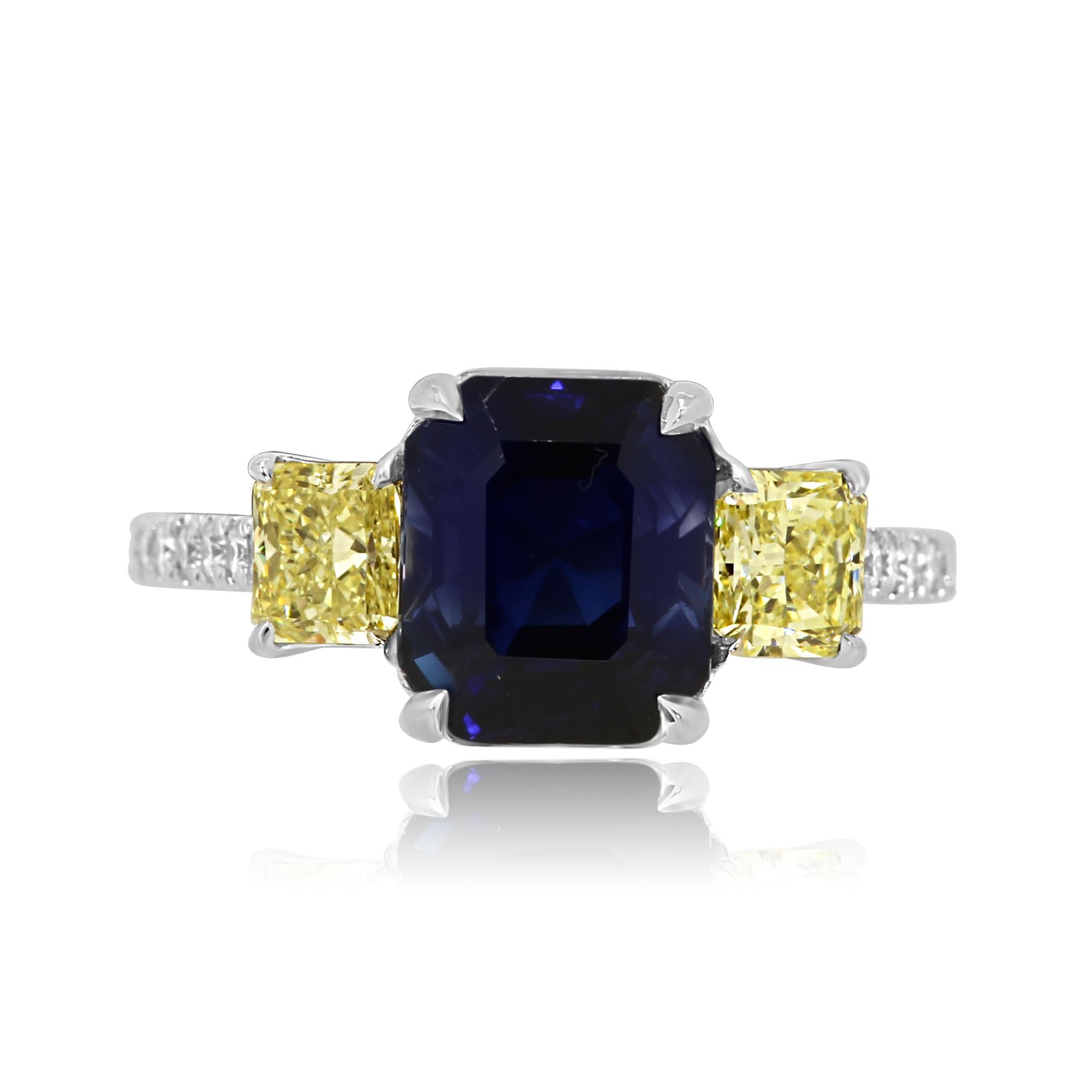Gorgeous Royal Blue GIA Certified 4.94 Carat NO HEAT Emerald Cut Madagascar Blue Sapphire Flanked with 2 Natural Fancy Yellow Radiant Cut Diamonds 0.86 Carat on the side set with white round diamonds 0.38 Carat on the Shank in Stunning 18K White