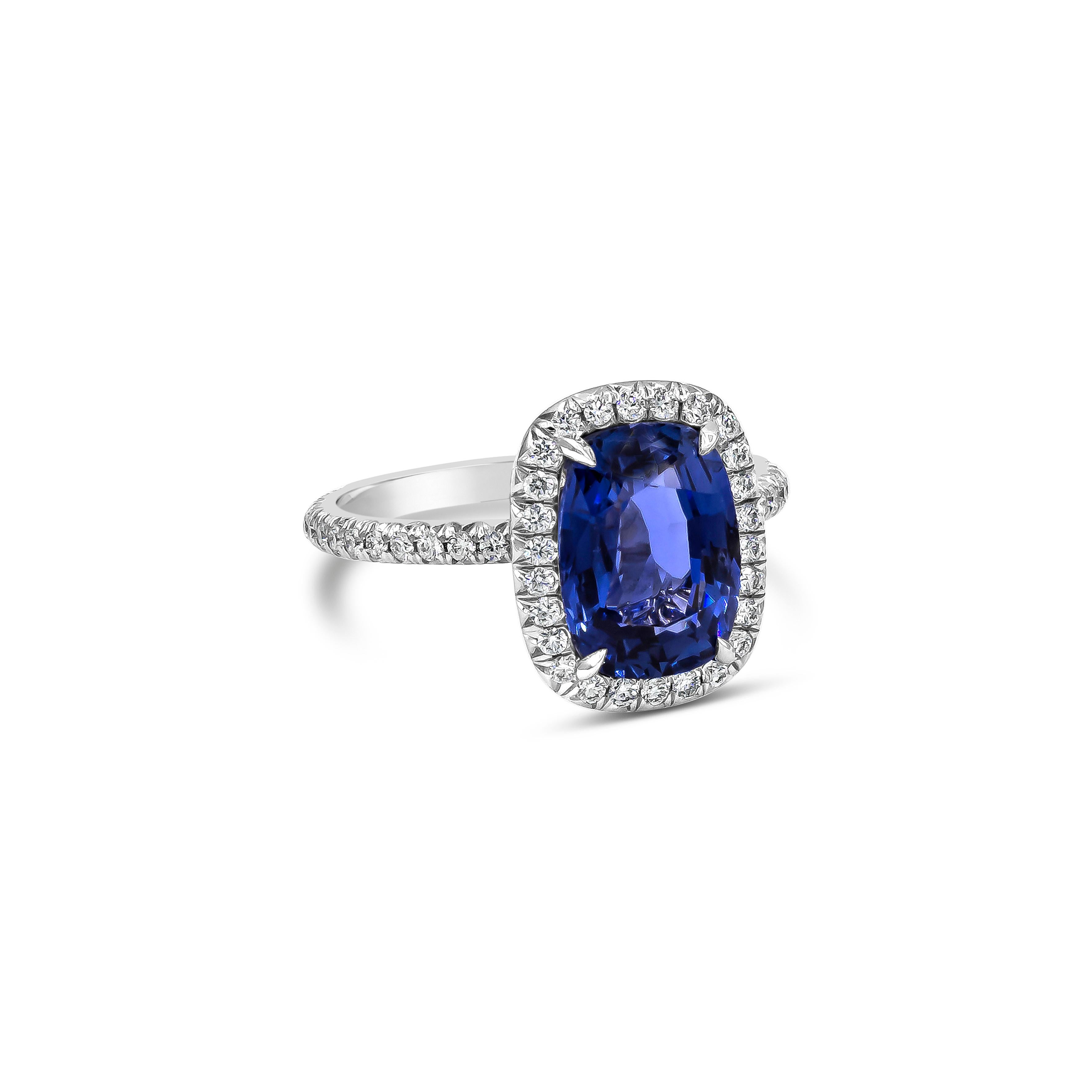 An elegant engagement ring, featuring a 3.37 carats cushion cut blue sapphire certified by GIA as blue color with no indications of heat, set on a four claw prong setting. Surrounded by a halo of round brilliant cut diamonds and accented by a