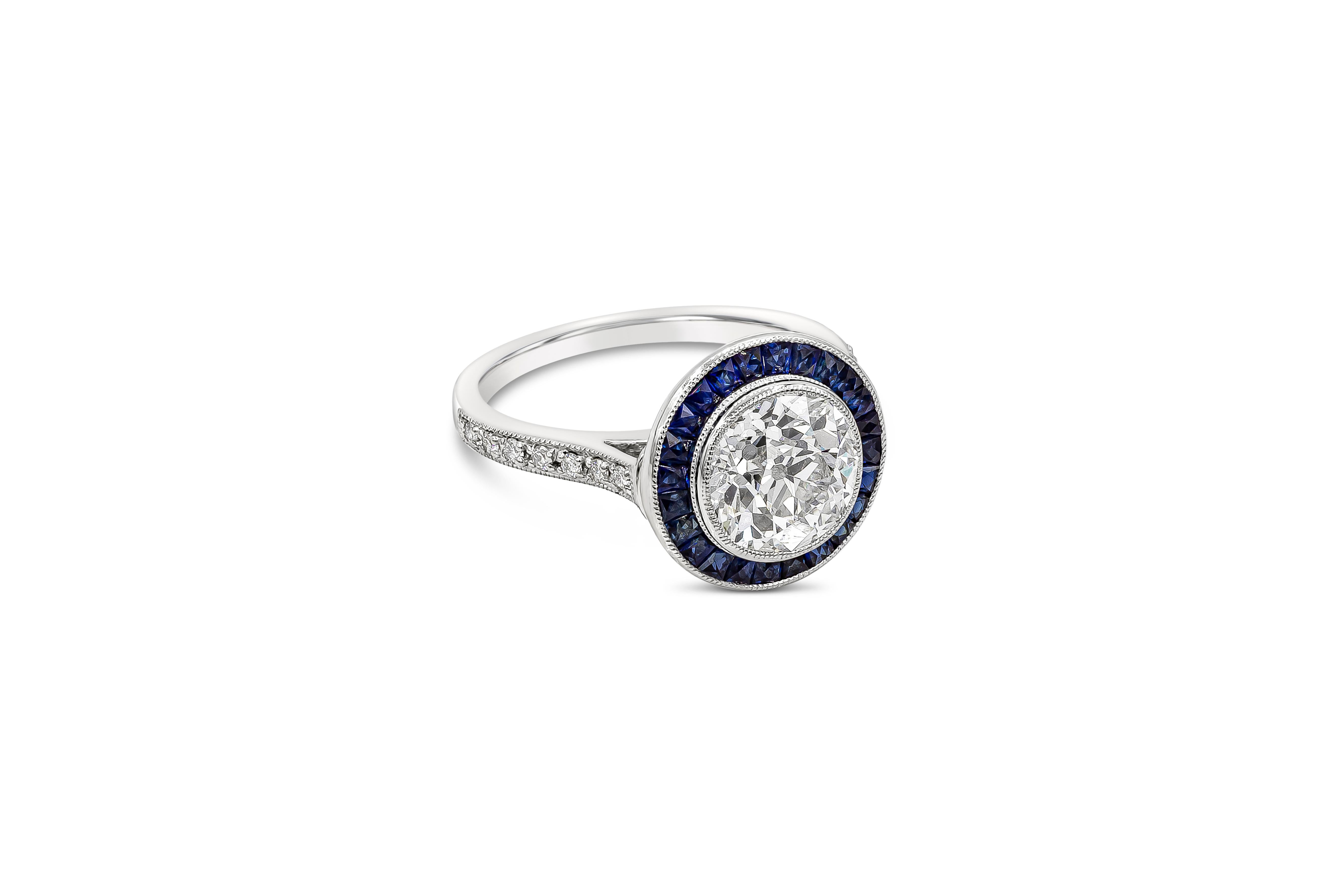 A vintage style engagement ring showcasing a GIA Certified 2.15 carat old European cut diamond, G Color and VS2 in Clarity. Center diamond is bezel set and surrounded by princess cut blue sapphires weighing 0.90 carats total. Center diamond is an