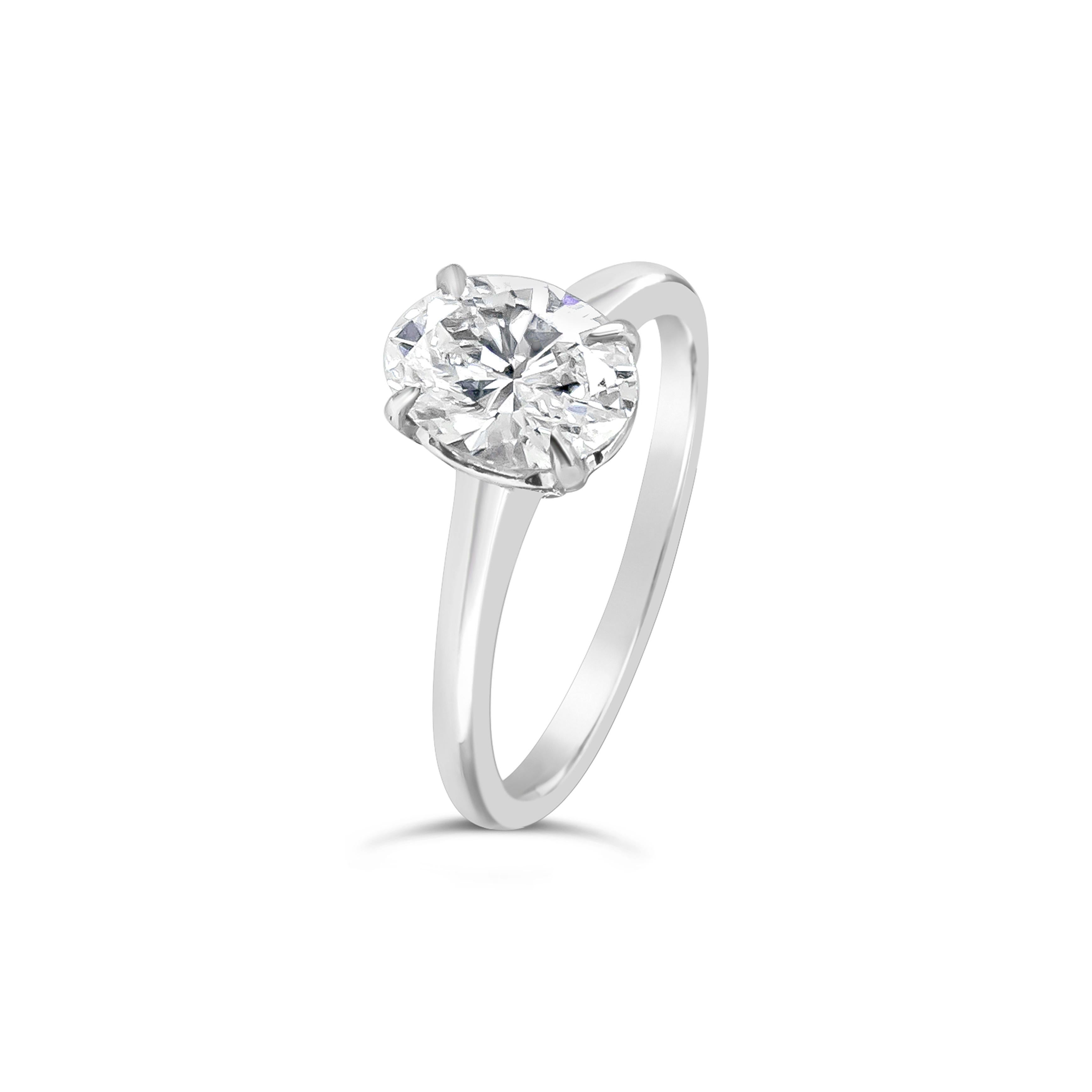 A timeless classic. Showcases a single brilliant oval cut diamond set in a 4 prong style basket. The basket is attached to a thin and rounded 18 karat white gold composition. GIA certified the diamond as E color, SI1 clarity. Size 5.25 US (Sizable