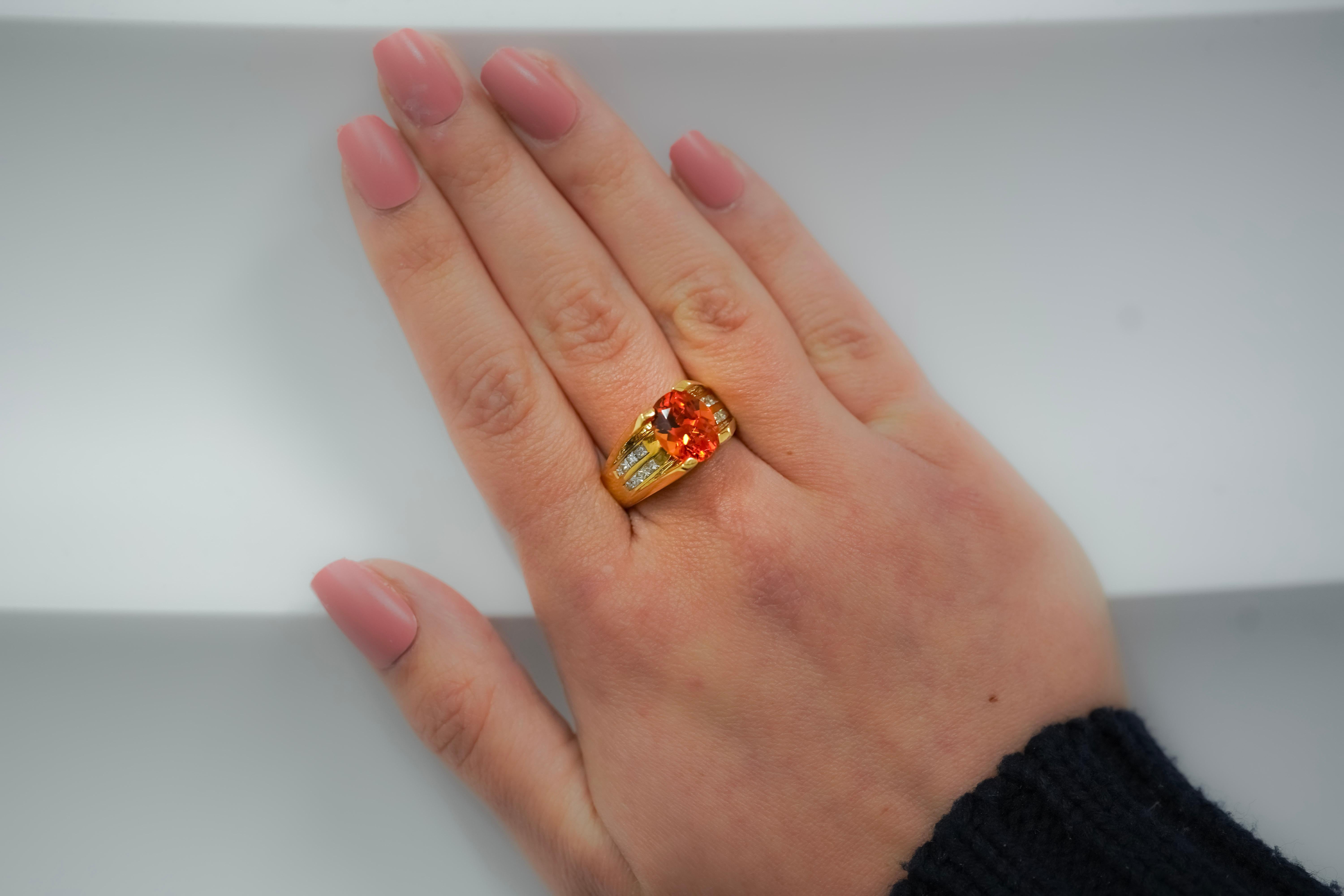 18K yellow gold oval cut Orange Spessartine Garnet and princess cut diamond ring. The Spessartine Garnet is mounted in a sharp, 4-prong setting that levitates the gem above the setting. Otherwise known as a floated set, for its optics as a gemstone