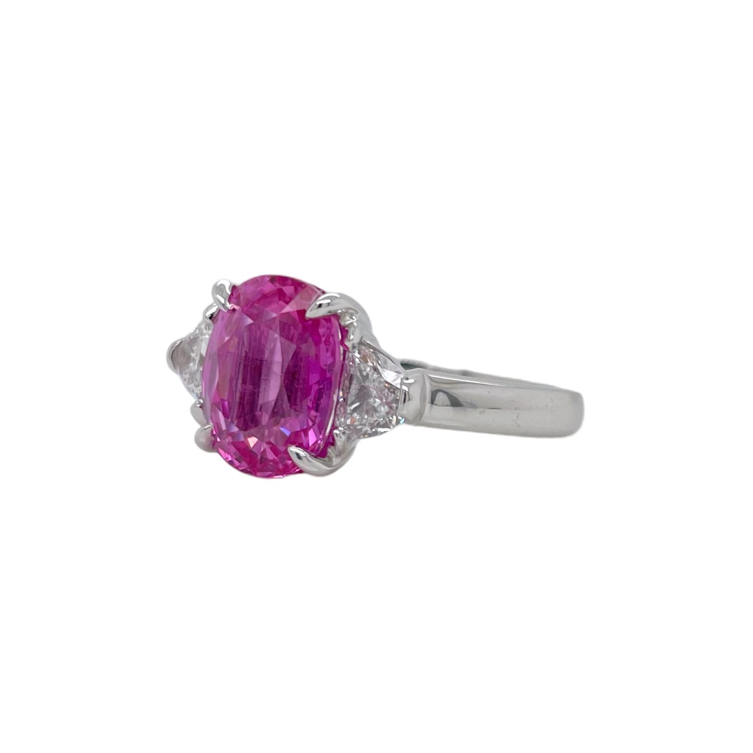 Ring contains one center GIA certified oval shape pink sapphire weighing 4.17ct. Center stone is accented by two side half moon cut diamonds weighing a total of 0.52cts. Pink Sapphire and diamonds are mounted in a handmade basket prong setting.