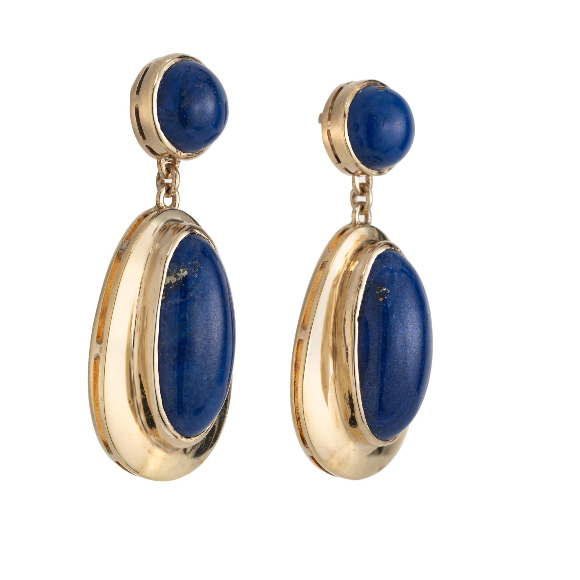 1960's Mid-Century oval round blue cabochon Lapis yellow gold dangle earrings are the perfect blend of elegance and modern style. 2 oval cabochon bezel Lapis that are mounted in 14k yellow gold settings. They are both accented by a round cabochon