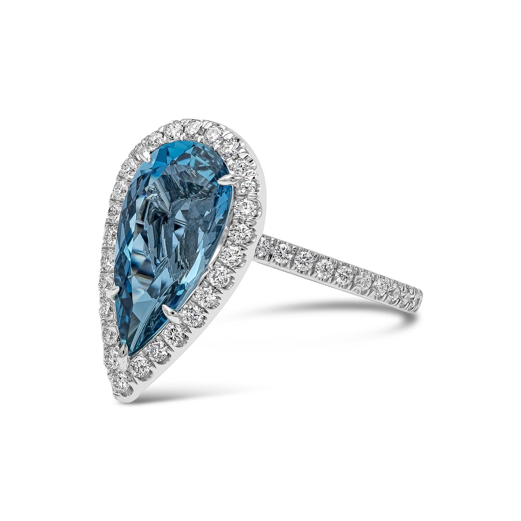 A beautiful engagement ring, showcasing a GIA certified 3.63 carats vivid blue pear shape aquamarine, set on a five claw prong setting. Surrounded by a halo of round cut diamonds and accented by a diamond encrusted shank in a pavé setting on a