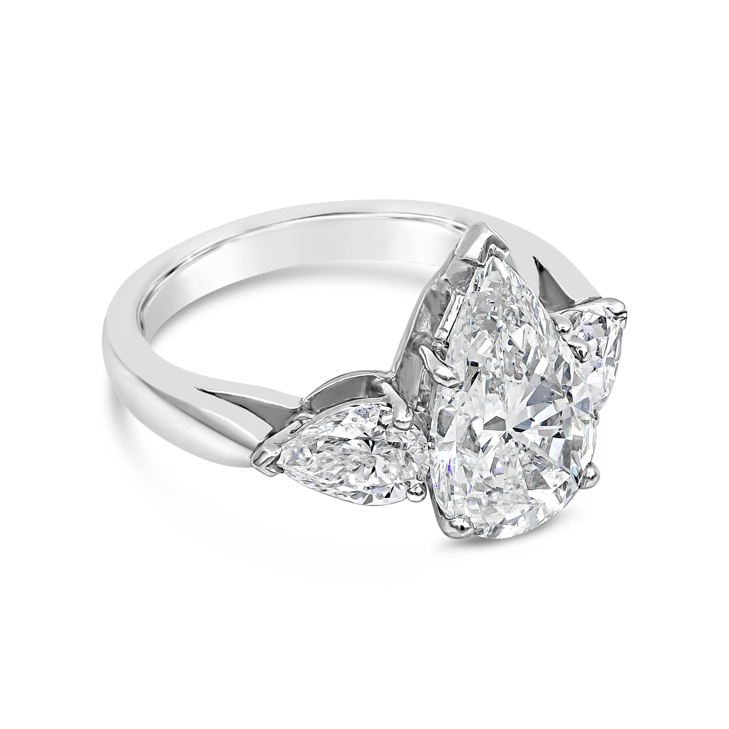 A classic engagement ring showcasing a 3.45 carat pear shape diamond, flanked by a smaller pear shape diamond on either side. Accent diamonds weigh 1.13 carats total. GIA certified the center diamond as G color, SI1 clarity. Made in platinum. Size