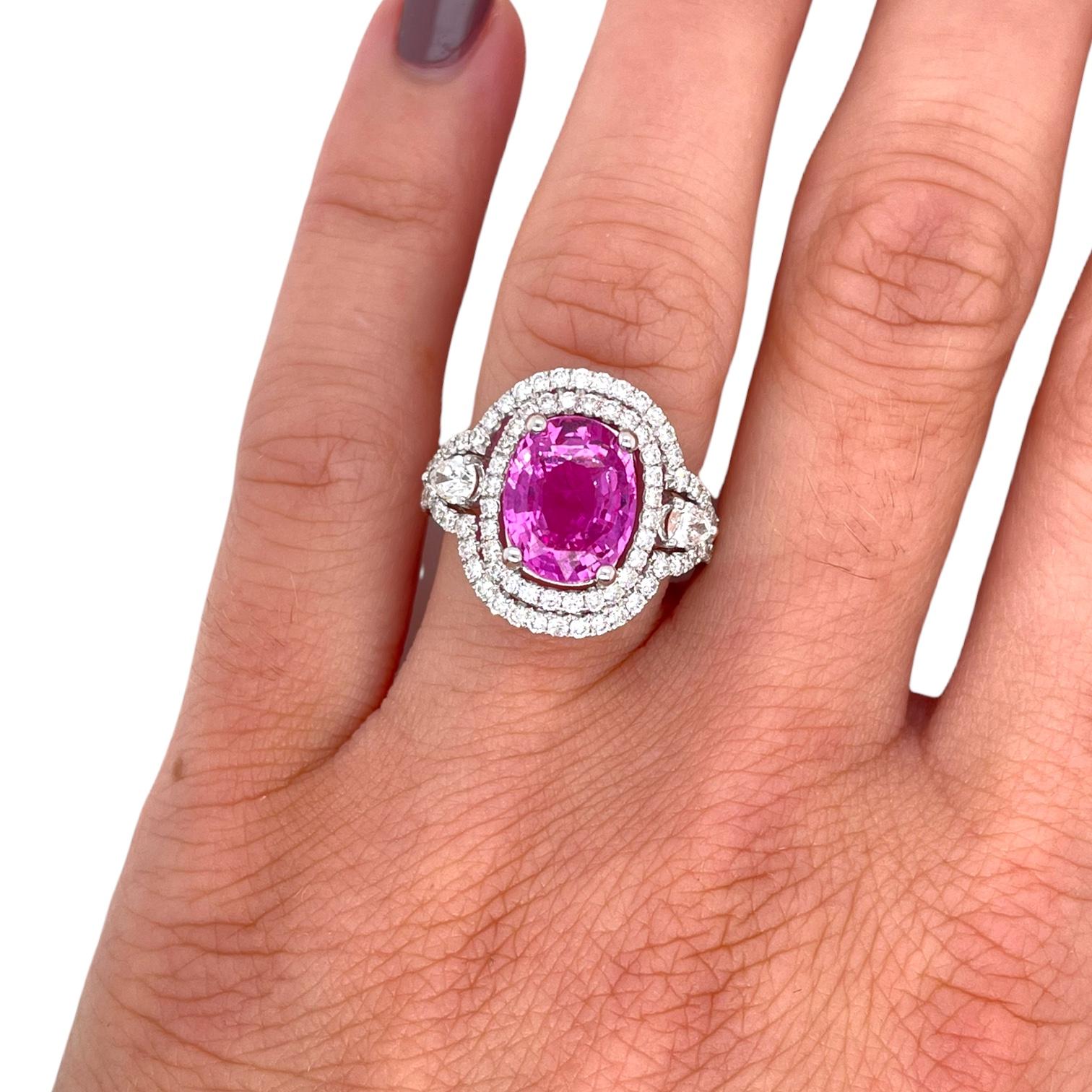 Gorgeous double halo pink sapphire and diamond ring in 18k white gold. Ring is centered around a brilliant oval shape pink sapphire weighing 4.08ct. Center stone is surrounded by a double row of round brilliant diamonds, 0.85tcw and two pear shape