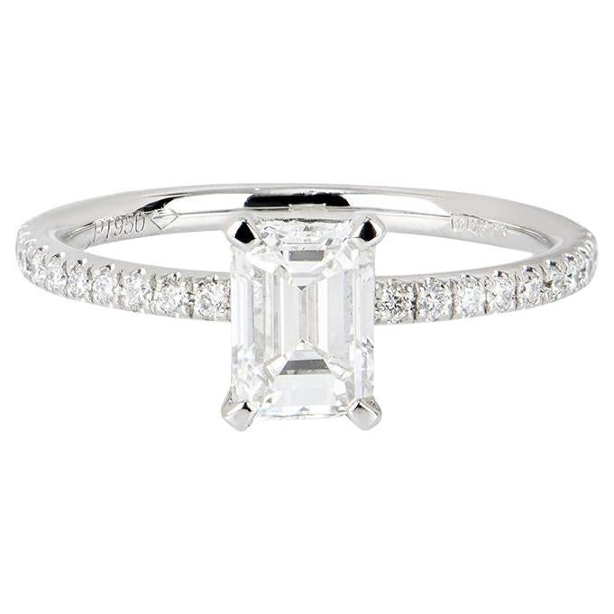 A gorgeous platinum diamond engagement ring. The ring features an emerald cut diamond set in a four claw mount weighing 0.97ct, G colour and VS2 clarity. The diamond is complemented by 22 round brilliant cut diamonds pave set to the shoulders. The