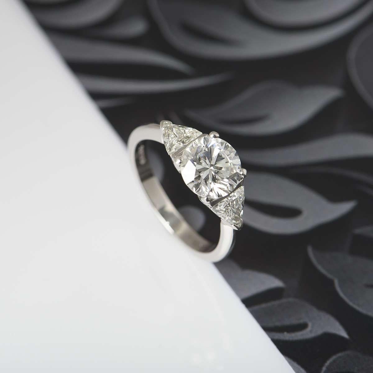 A diamond engagement ring in platinum. The central round brilliant cut diamond weighs 2.08ct, is I colour and I3 clarity. There are two trilliant cut diamonds set to either side totalling approximately 0.90ct. The ring is currently a size UK N / EU
