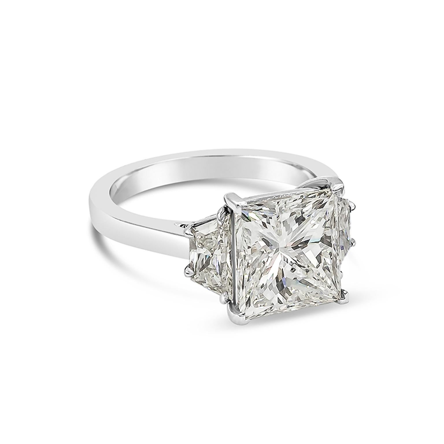 a classic engagement ring style showcasing a 4.03 carat princess cut diamond certified by GIA as J color, SI1 clarity. Flanking the center stone are brilliant trapezoid diamonds weighing 0.95 carats total. Set in a polished platinum mounting. Size
