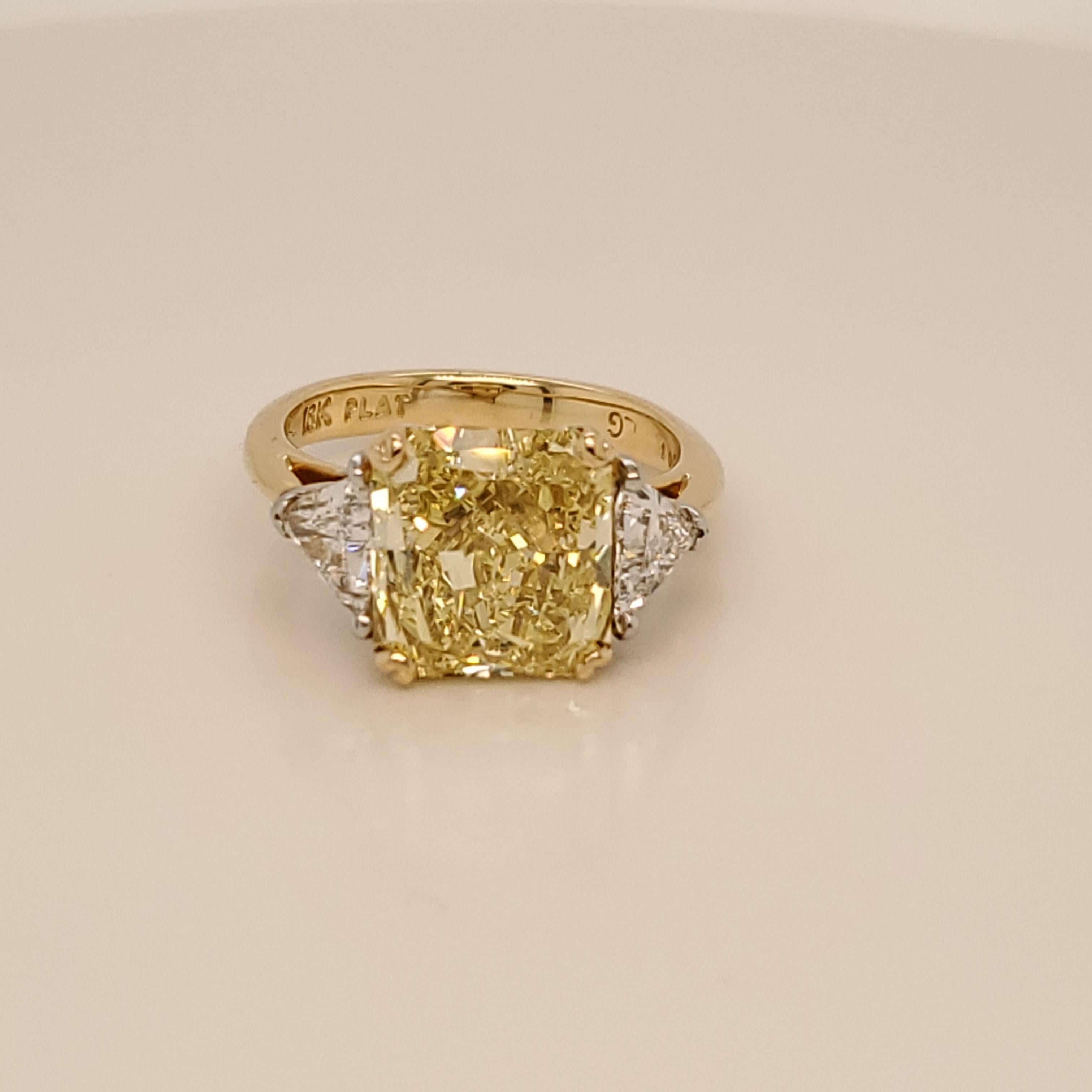 GIA Certified canary Three Stone Ring. The center stone is a Radiant cut Fancy Intense Yellow and SI1 Clarity. The two side stones are triangular shaped diamonds weighing 0.93 carats total. G color and SI1 clarity. The ring is made up of platinum