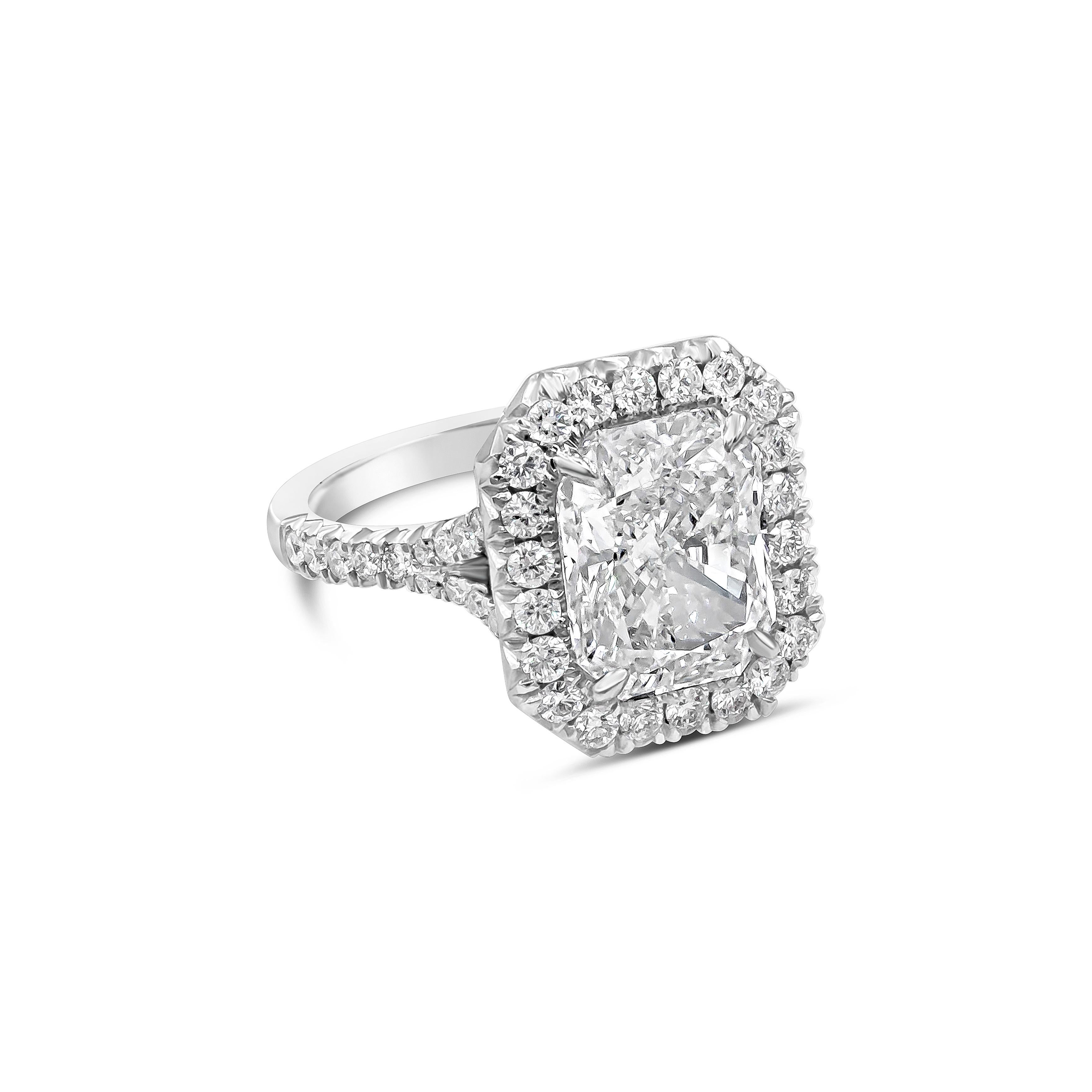 An elegant engagement ring, showcasing a 4.15 carats radiant cut diamond certified by GIA as G color and VS2 clarity, set on a four prong setting. Surrounded by a halo of round brilliant cut diamonds and accented by a diamond encrusted semi