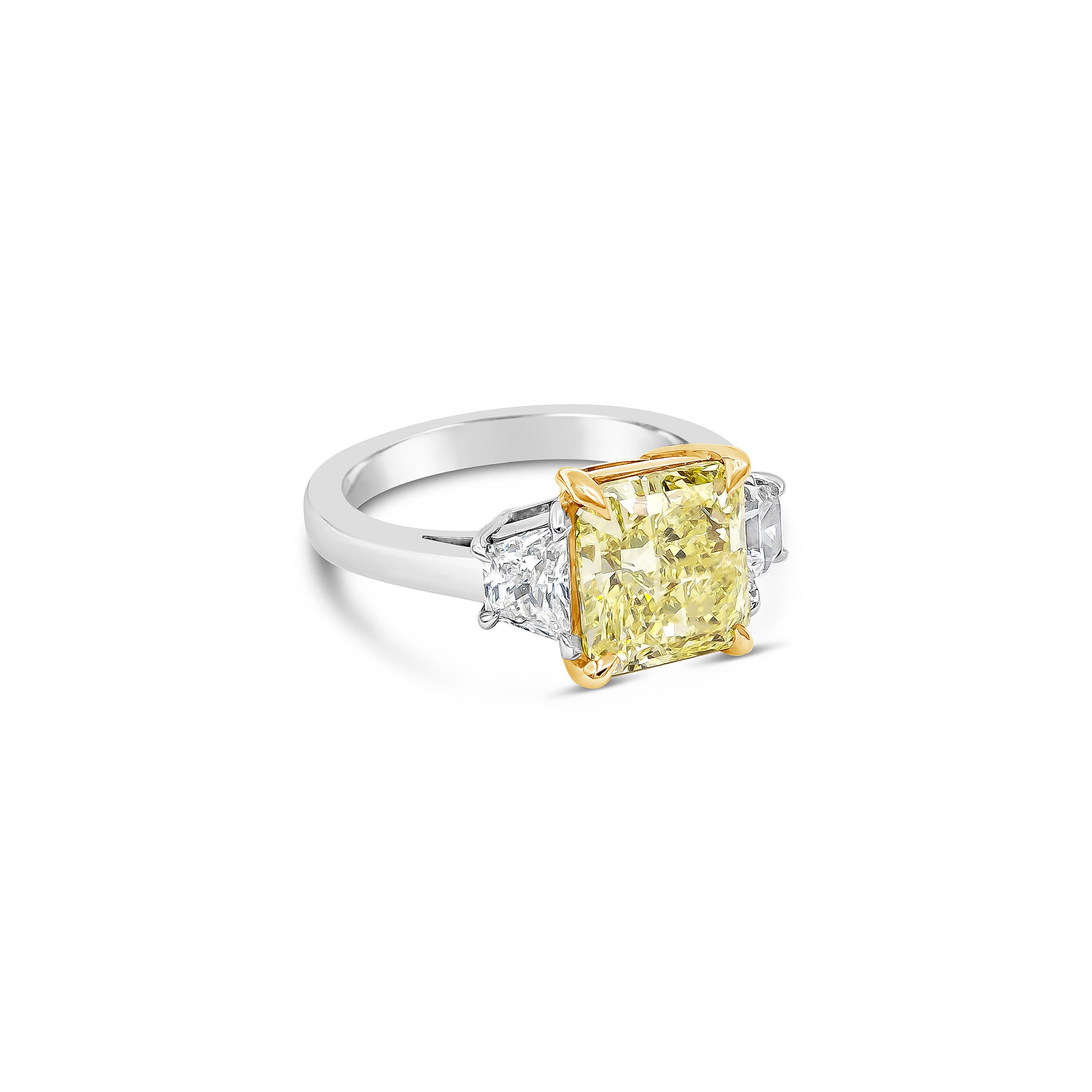 Features a 3.31 carats radiant cut diamond that GIA certified as Fancy Yellow color, VVS2 in clarity, set in a 18k yellow gold four prong basket setting. Elegantly flanked by two trapezoid diamonds in a platinum mounting and composition weighing