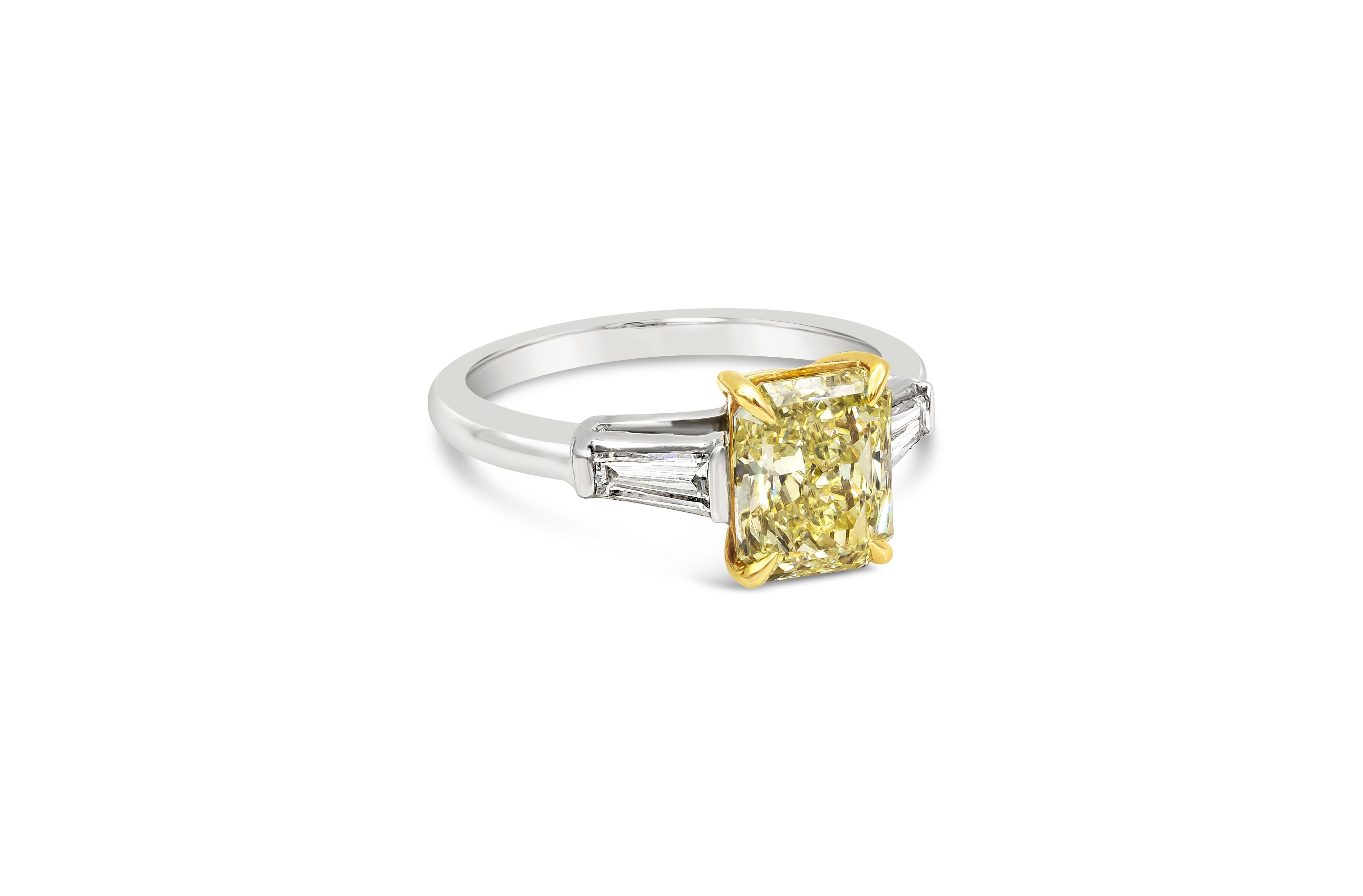 A classic engagement ring style showcasing a 2.05 carat radiant cut diamond certified by GIA as Fancy Light Yellow, VVS2 clarity. Flanking the center diamond are tapered baguette diamonds on either side. Set in a polished platinum mounting. Size