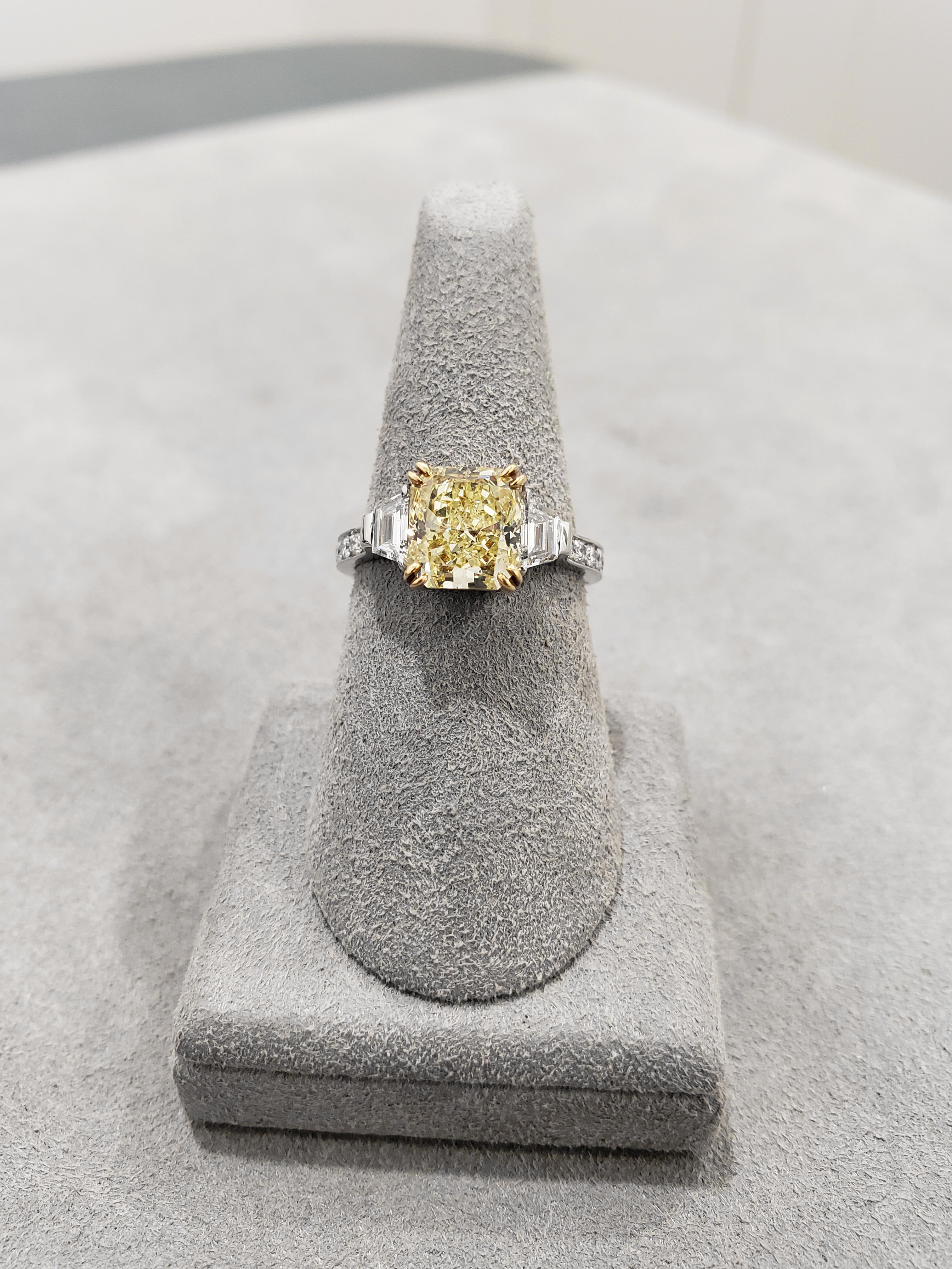 A color-rich engagement ring showcasing a gorgeous 2.52 carat radiant cut yellow diamond securely set in a double eagle prong yellow gold basket. GIA Certified the center diamond as Fancy Yellow color, VS1 clarity. Step-cut trapezoid diamonds