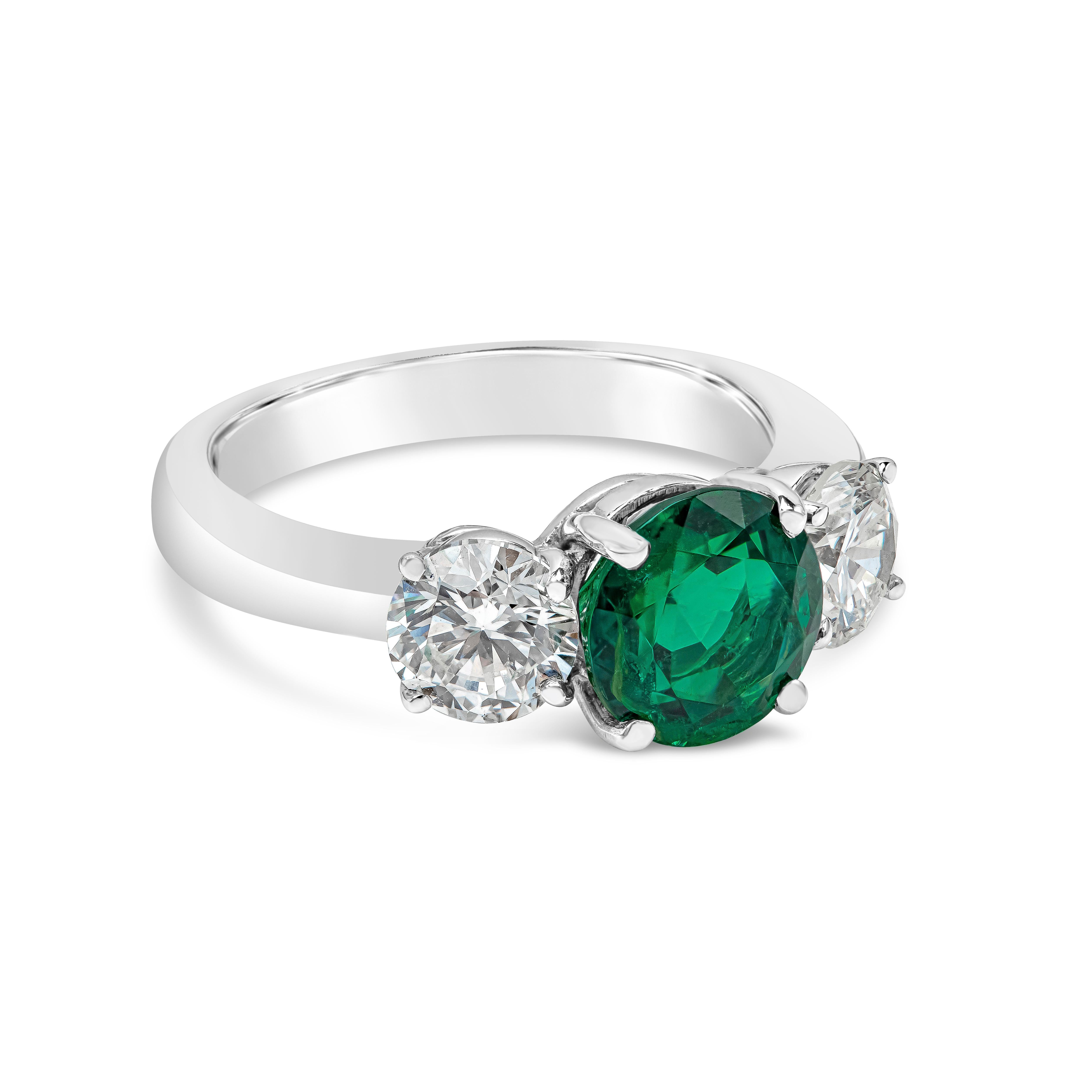 Elegantly made three stone engagement ring showcasing a rare vibrant green emerald weighing 1.87 carats and is certified by GIA as Russian origin. Flanking the center gemstone are two round brilliant diamonds weighing 1.30 carats total, G-H color