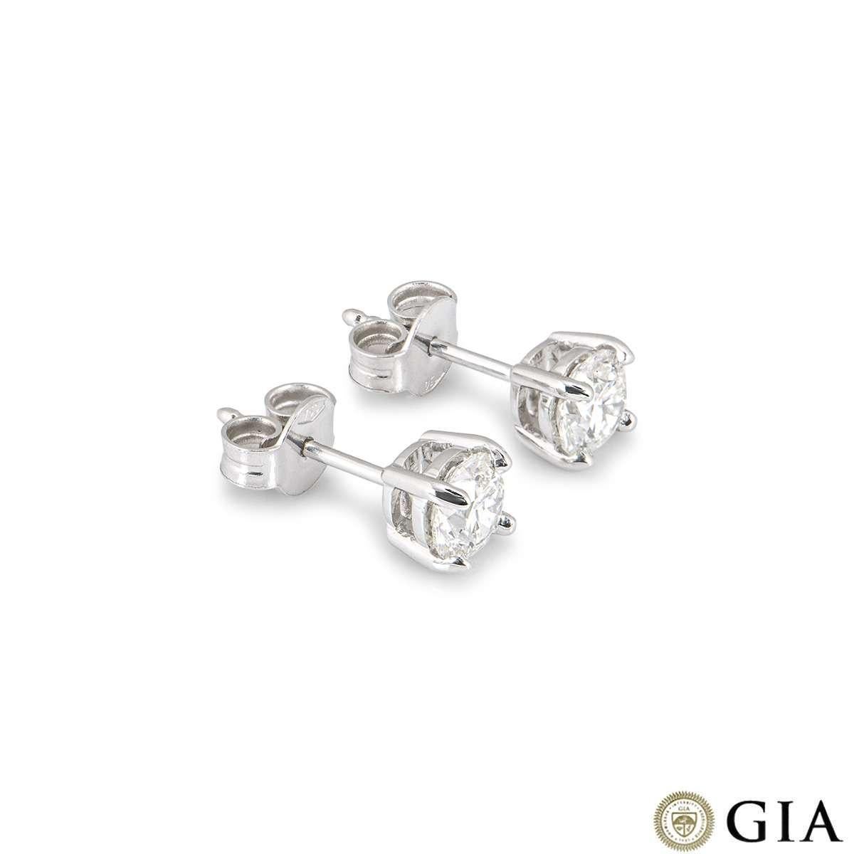 A pair of 18k white gold diamond stud earrings. The earrings feature round brilliant cut diamonds in a 4 claw setting. Both diamonds weigh 0.60ct each, one is G colour and the other is H colour, both VS2 in clarity. The earrings have post and