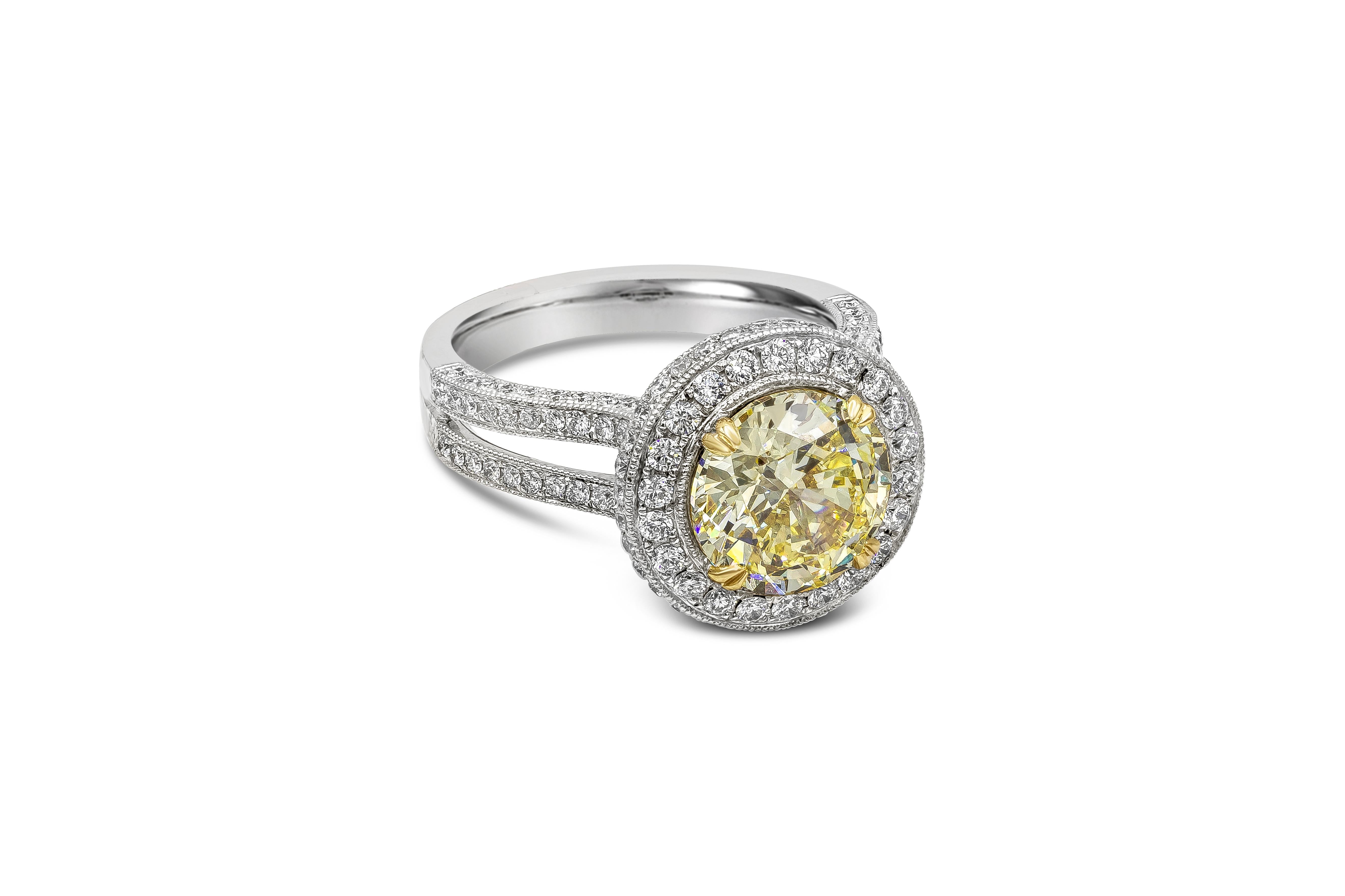 A vintage looking engagement ring showcasing a GIA certified 3.08 carat round fancy yellow diamond, Accented with round melee diamond in a halo design weighing 1.04 carats total. SI1 in Clarity. Set in a diamond encrusted split-shank setting, Made